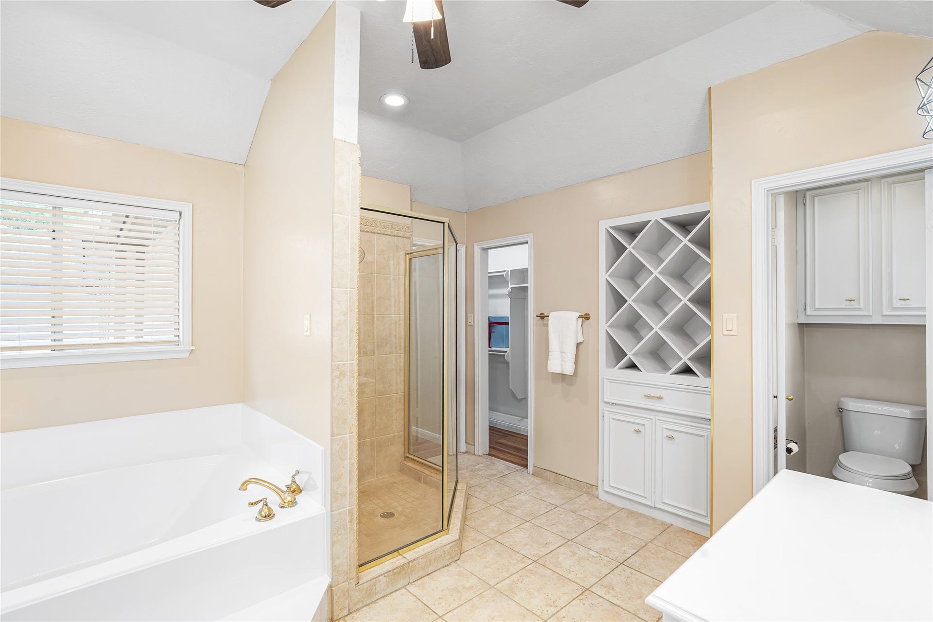 Luxurious soaking tub, elegant walk-in shower, and ample storage with a wine rack design.