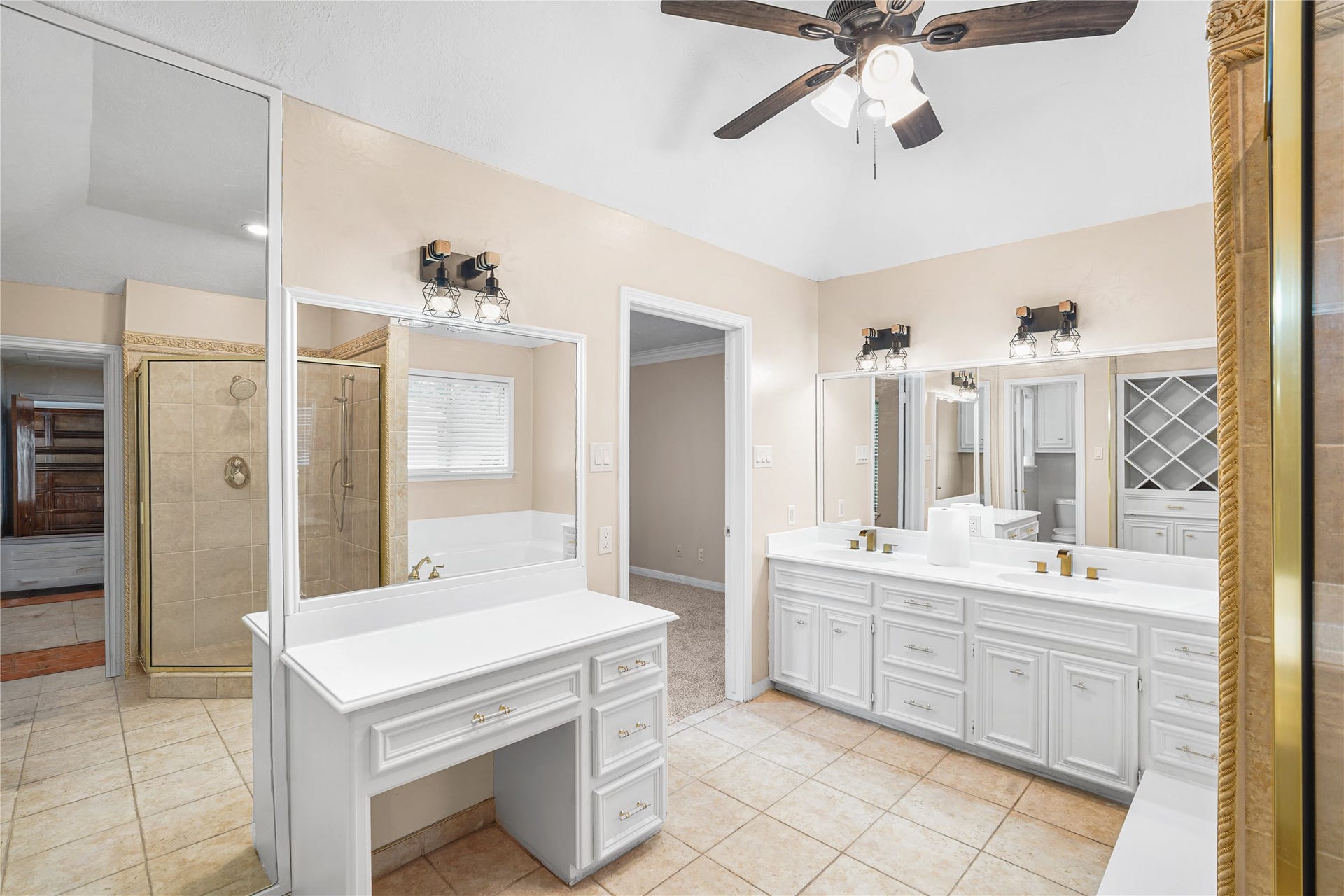 Spacious Primary bathroom featuring dual vanities, elegant lighting, and a large walk-in shower, complemented by a stylish ceiling fan and ample natural light.