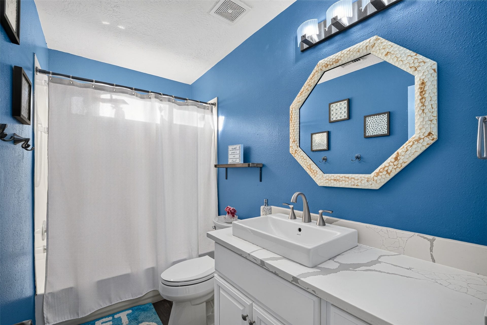 113 Erin Court, La Porte, TX 77571 Full bath with blue walls and a stylish octagonal mirror.