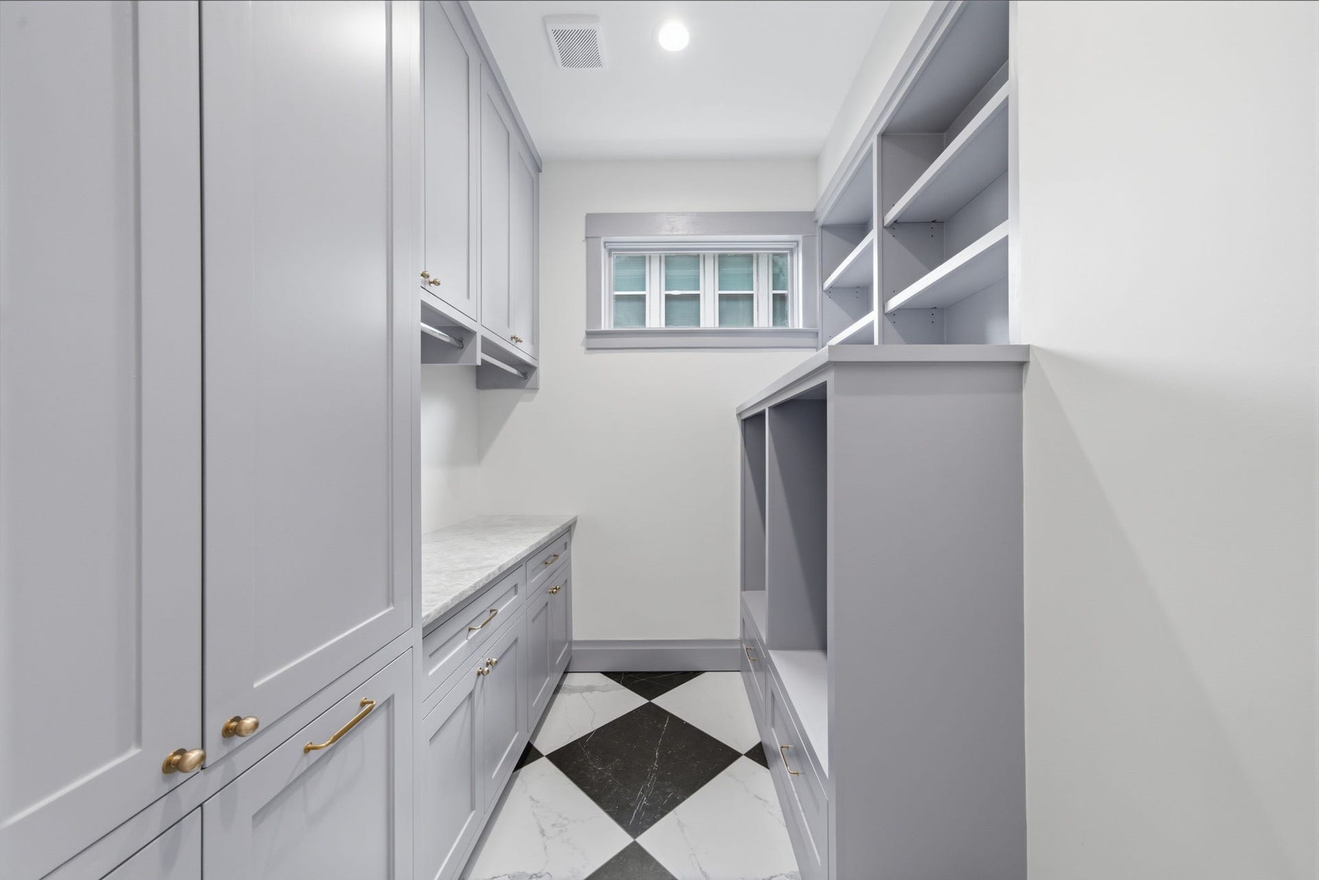 404 Avondale Street, Houston, TX 77006 Elegant laundry with ample storage, featuring sleek gray cabinetry, Quartzite countertops, and a stylish black-and-white tiled floor.
