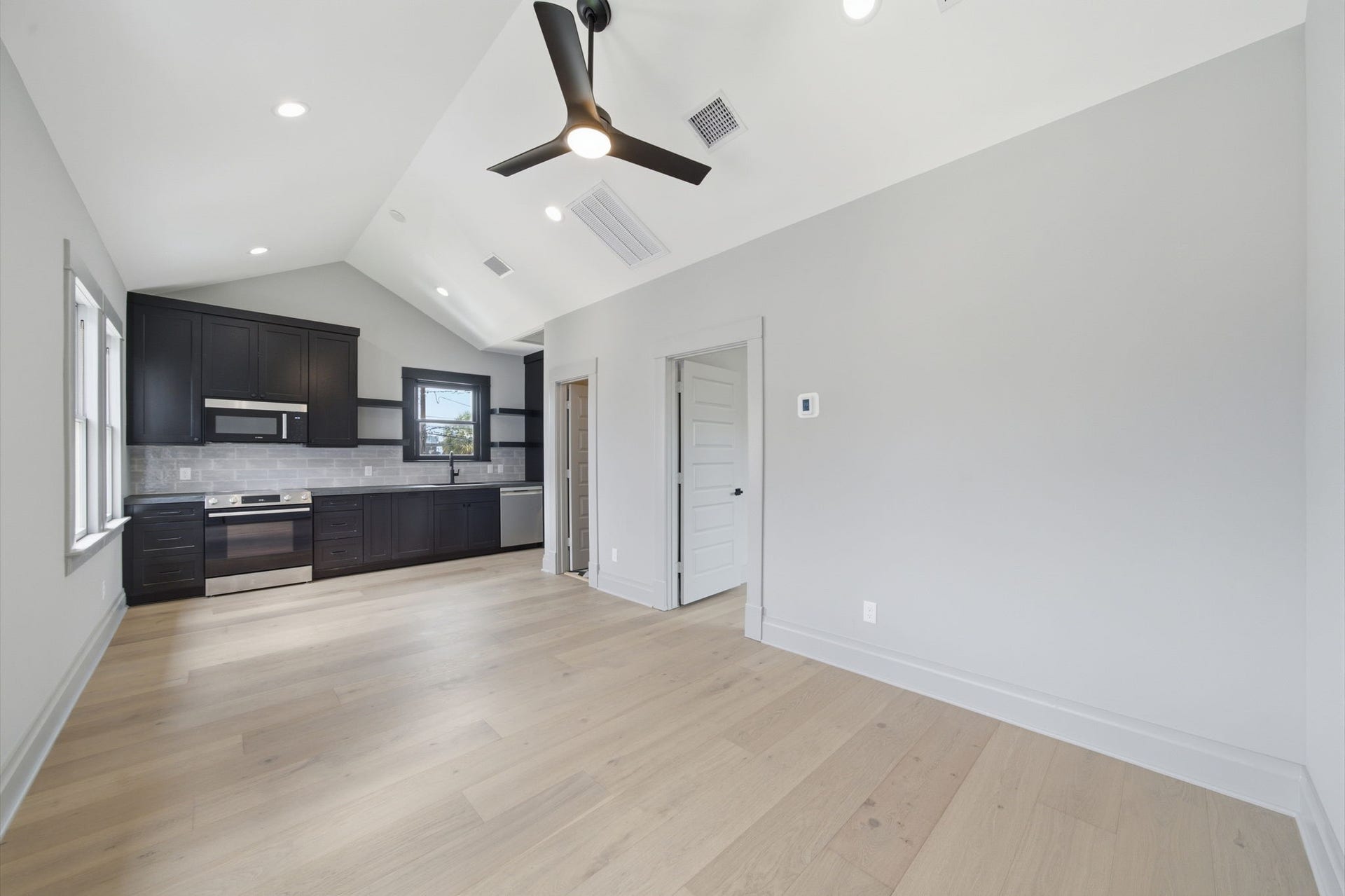 404 Avondale Street, Houston, TX 77006 The apartment brings bright, open-concept space with vaulted ceilings and sleek hardwood floors, featuring a modern kitchen with dark cabinetry and stainless steel appliances.