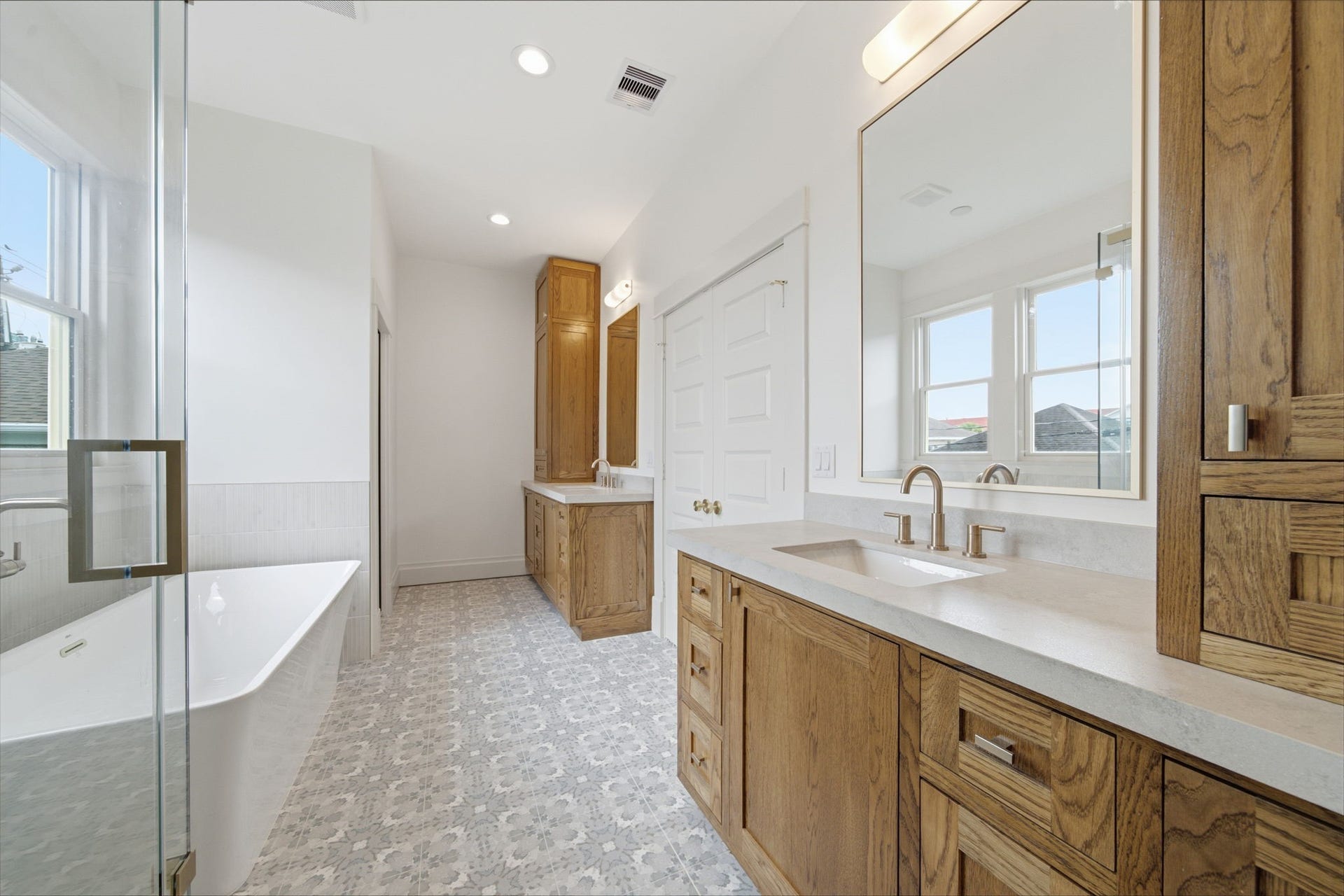 404 Avondale Street, Houston, TX 77006 Primary bathroom featuring a spacious double vanity with rich wooden cabinetry, a sleek bathtub, and large windows allowing abundant natural light.