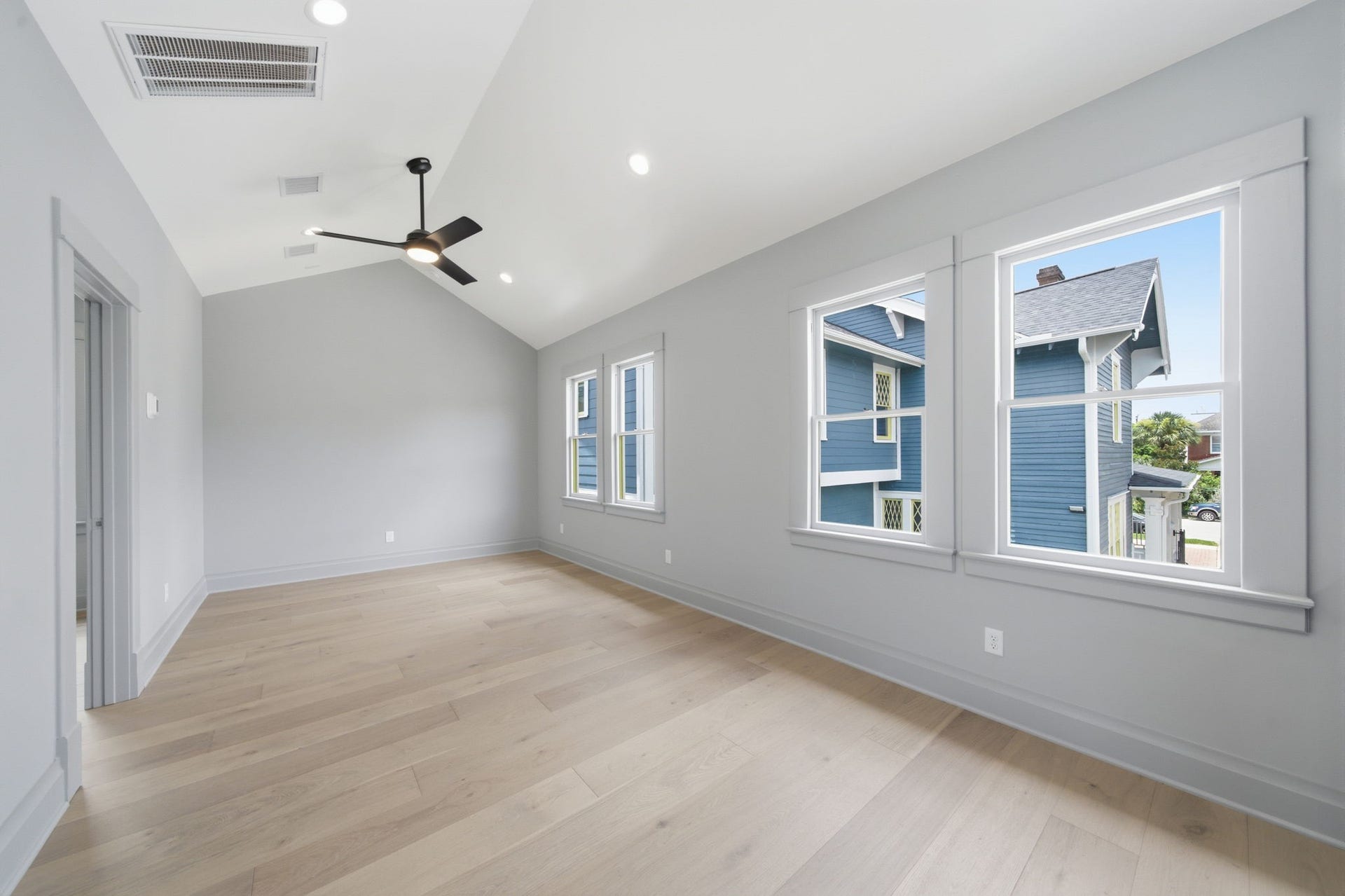 404 Avondale Street, Houston, TX 77006 Spacious and bright room with vaulted ceilings, large windows, and sleek light wood floors, perfect for a modern touch.