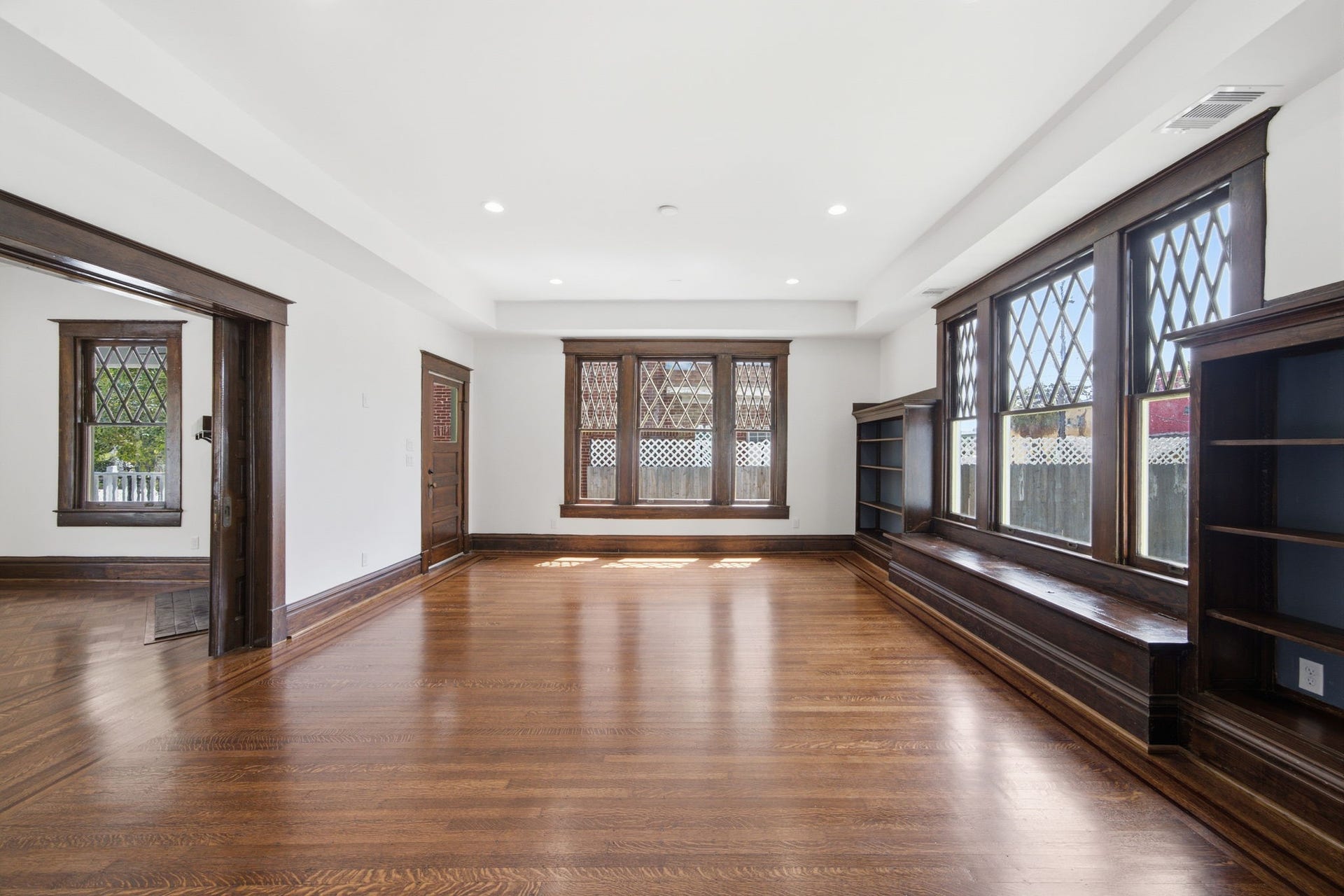 404 Avondale Street, Houston, TX 77006 Spacious living area featuring elegant wood flooring, built-in shelving, and large windows with decorative lattice details, offering ample natural light and a classic charm.