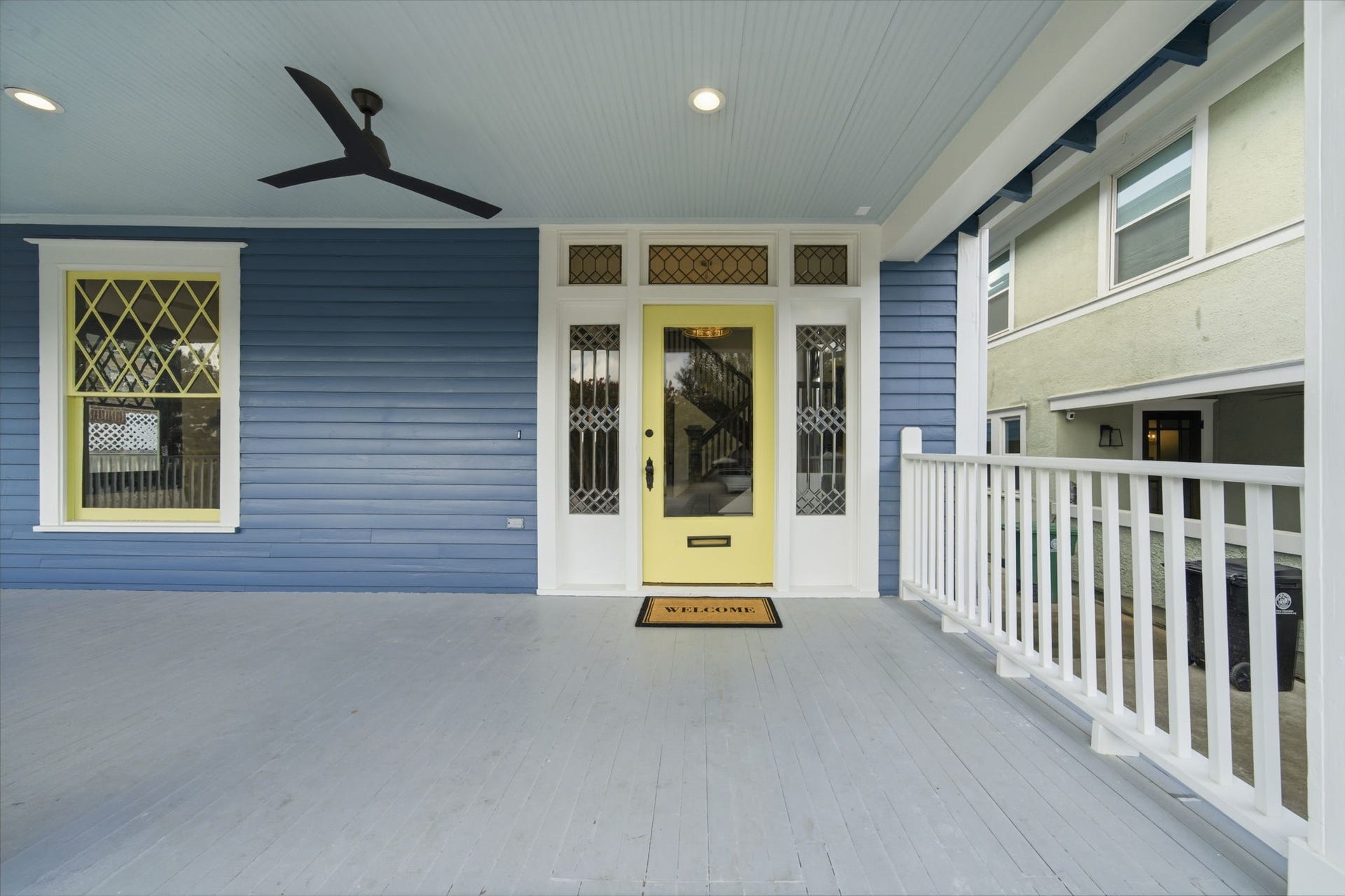 404 Avondale Street, Houston, TX 77006 Original front door! A vibrant yellow door, classic blue siding, and elegant white railing, perfect for relaxing afternoons.