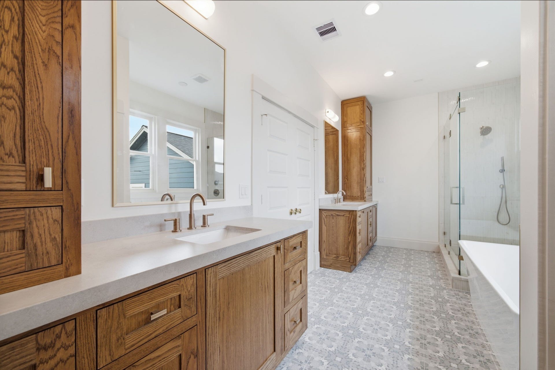 404 Avondale Street, Houston, TX 77006 The primary bathroom featuring elegant wooden cabinets, dual sinks, and a large glass-enclosed shower complemented by stylish tile flooring.