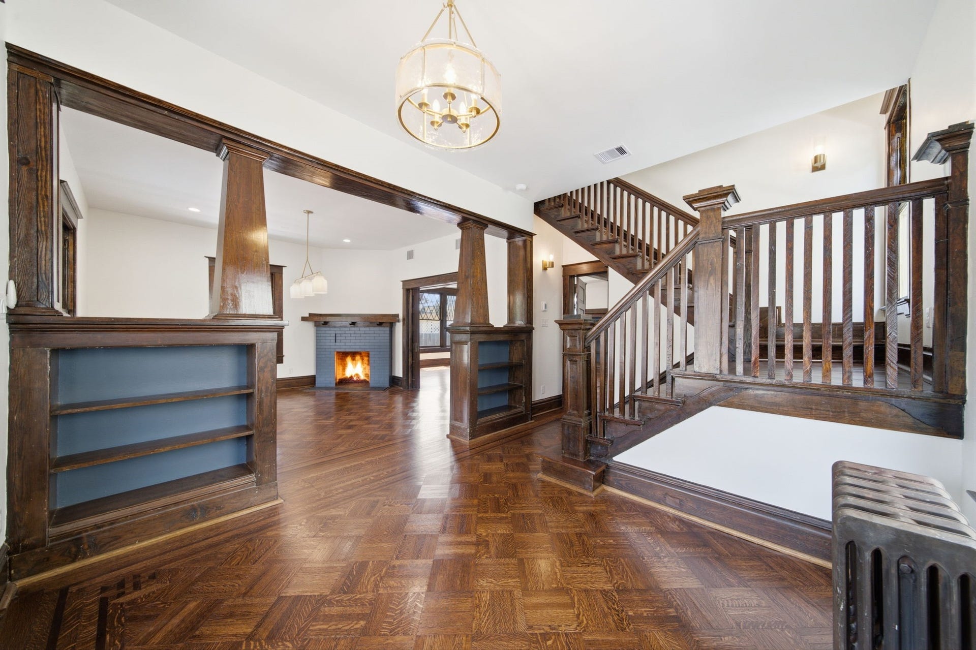 404 Avondale Street, Houston, TX 77006 Charming living space featuring rich wood paneling, a cozy fireplace, and elegant hardwood floors, complemented by an impressive staircase and built-in shelving.