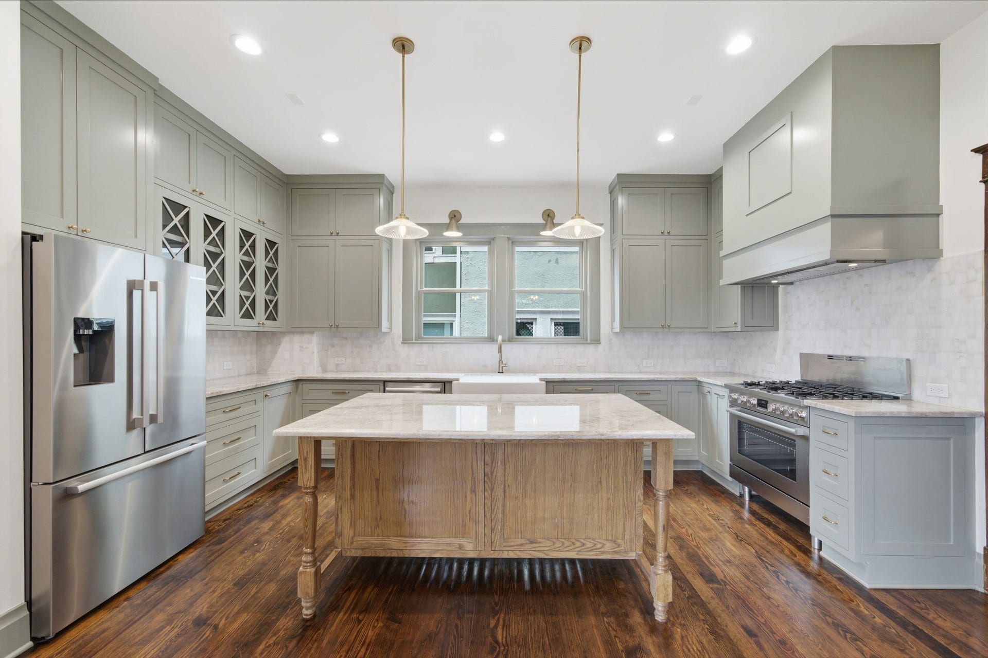 404 Avondale Street, Houston, TX 77006 Spacious kitchen featuring elegant cabinetry, a central island with a marble countertop, stainless steel appliances, and warm hardwood floors.