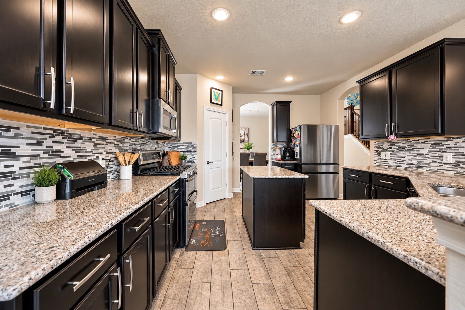 The double oven and central island are perfect for culinary enthusiasts while the sleek dark cabinetry and updated floor tile sets the mood!