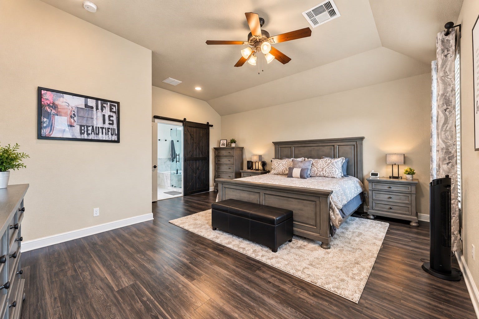 The primary retreat! Elegant flooring and vaulted ceilings elevate the vibe here and there's even space for a cozy seating area!