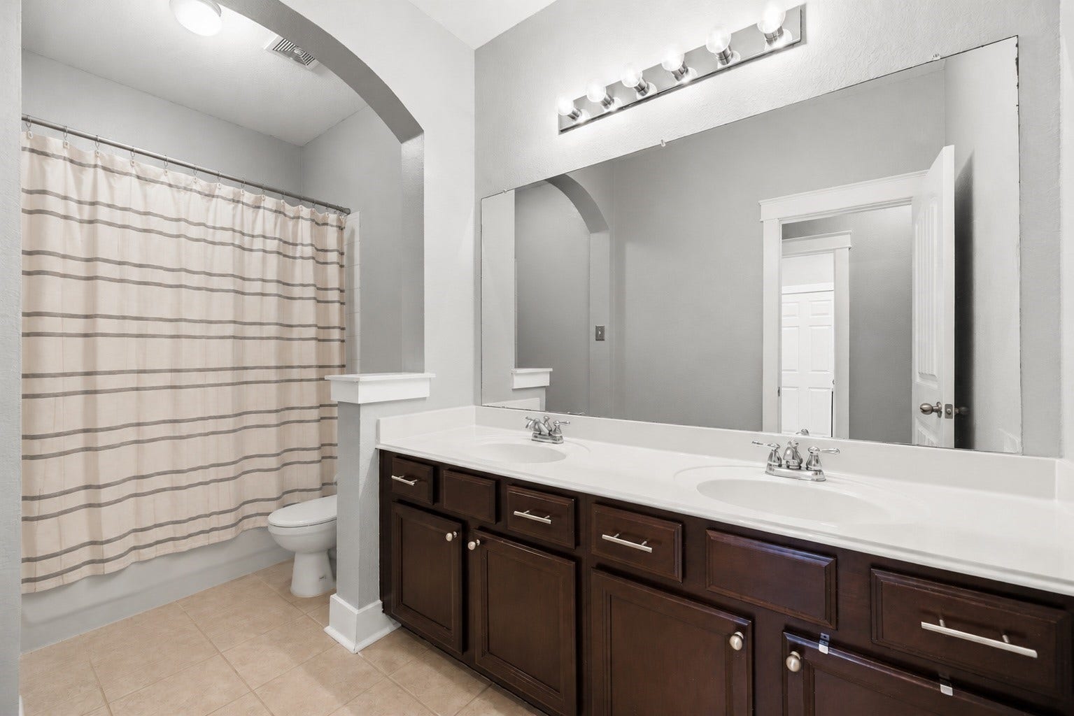 20918 Field Manor Lane, Katy, TX 77450 Spacious bathroom featuring a double vanity with elegant dark wood cabinets, a large mirror, and a cozy shower-tub combo.