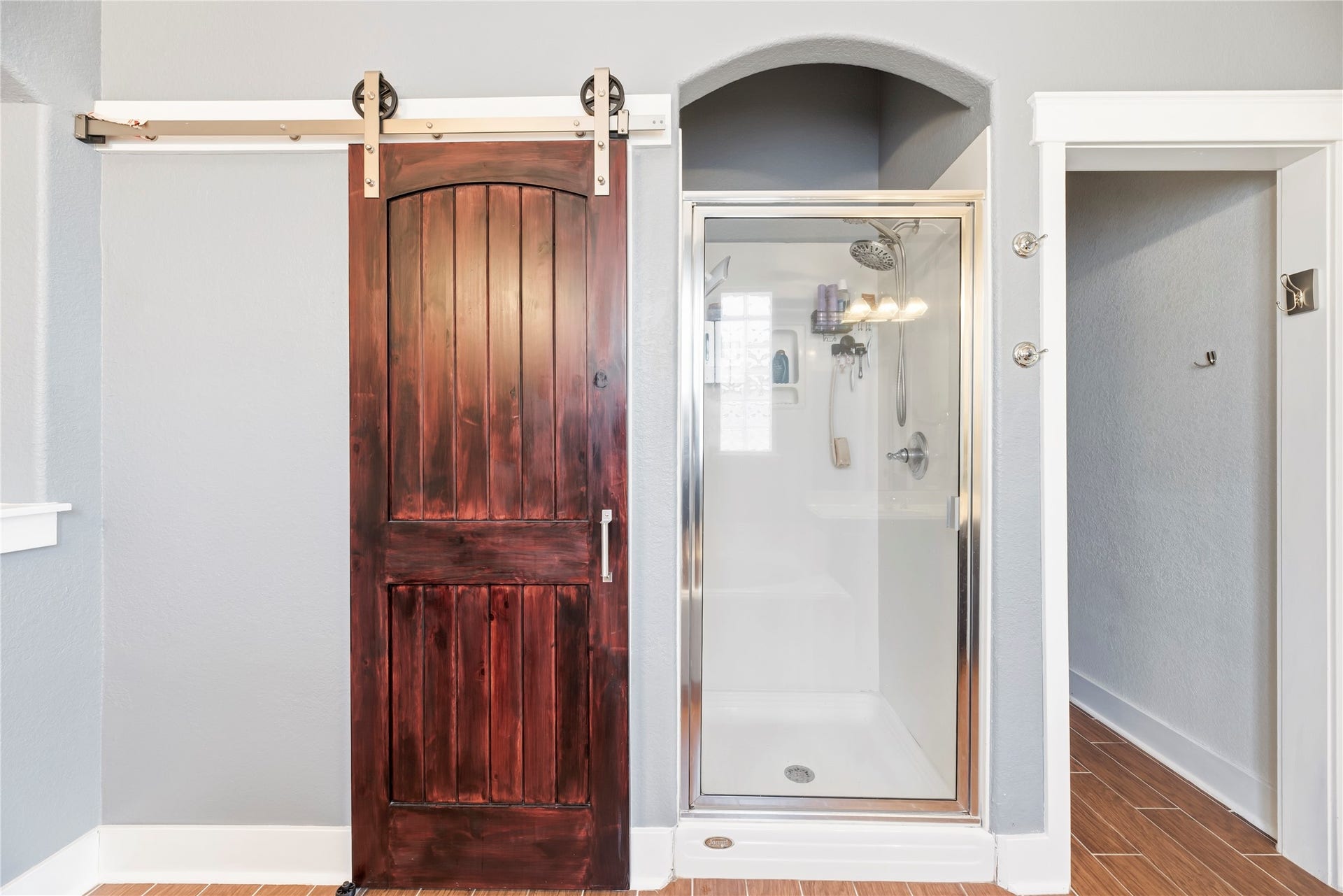 20918 Field Manor Lane, Katy, TX 77450 Elegant bathroom featuring a sleek glass shower, rich wooden barn door, and modern gray walls, creating a stylish and functional space.