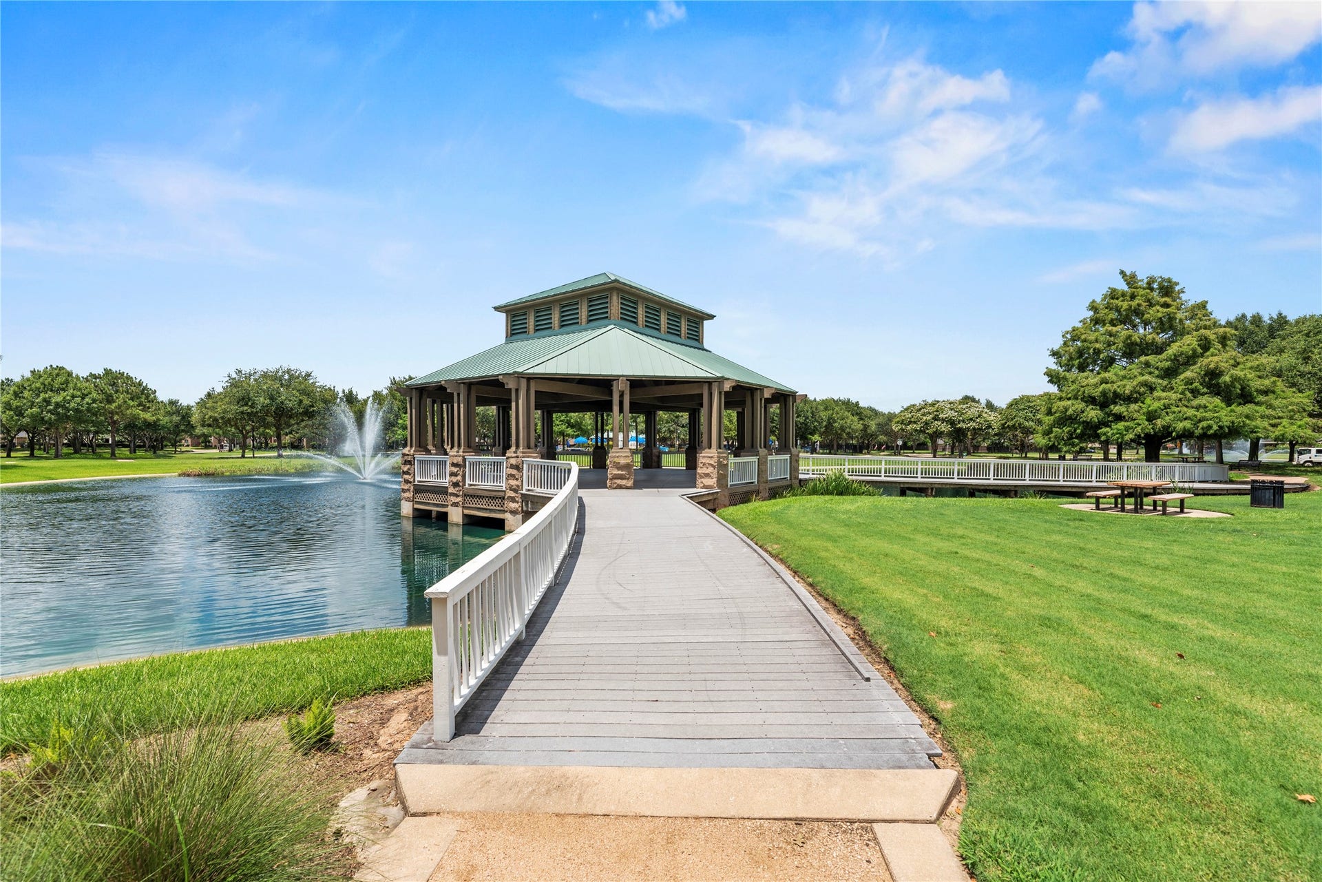 20918 Field Manor Lane, Katy, TX 77450 A gazebo overlooking a tranquil pond with a fountain, surrounded by lush greenery and walking paths, perfect for relaxation and outdoor gatherings.