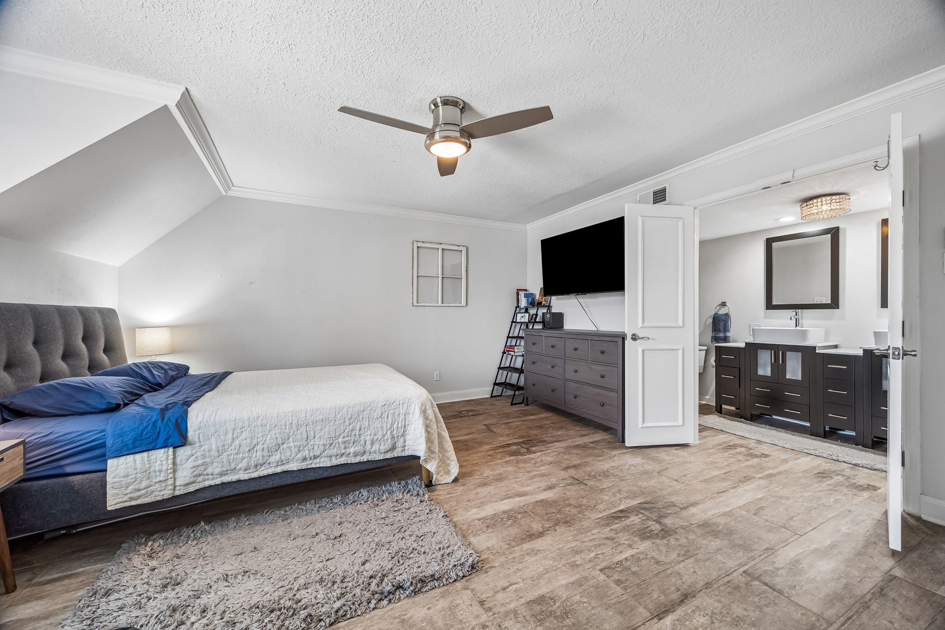 14719 Barryknoll Lane, #51, Houston, TX 77079 The spacious primary bedroom offers wood-look flooring, crown molding, and a ceiling fan for everyday comfort. The adjoining ensuite is easily accessible and features a wide vanity with generous storage.