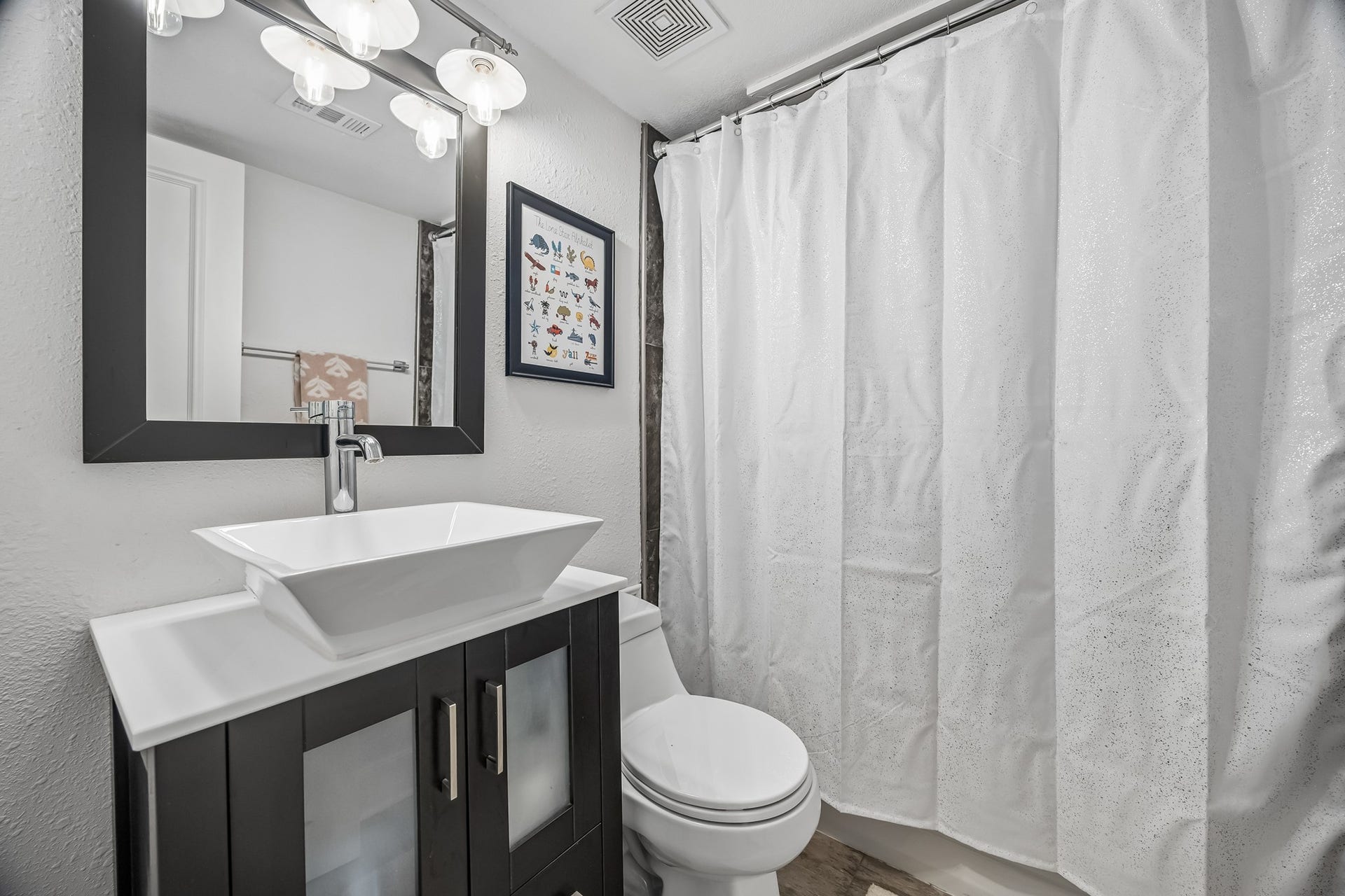 14719 Barryknoll Lane, #51, Houston, TX 77079 The secondary bathroom features a modern vanity with a vessel sink, framed mirror, and updated lighting. A tub/shower combination provides everyday convenience for family or guests.
