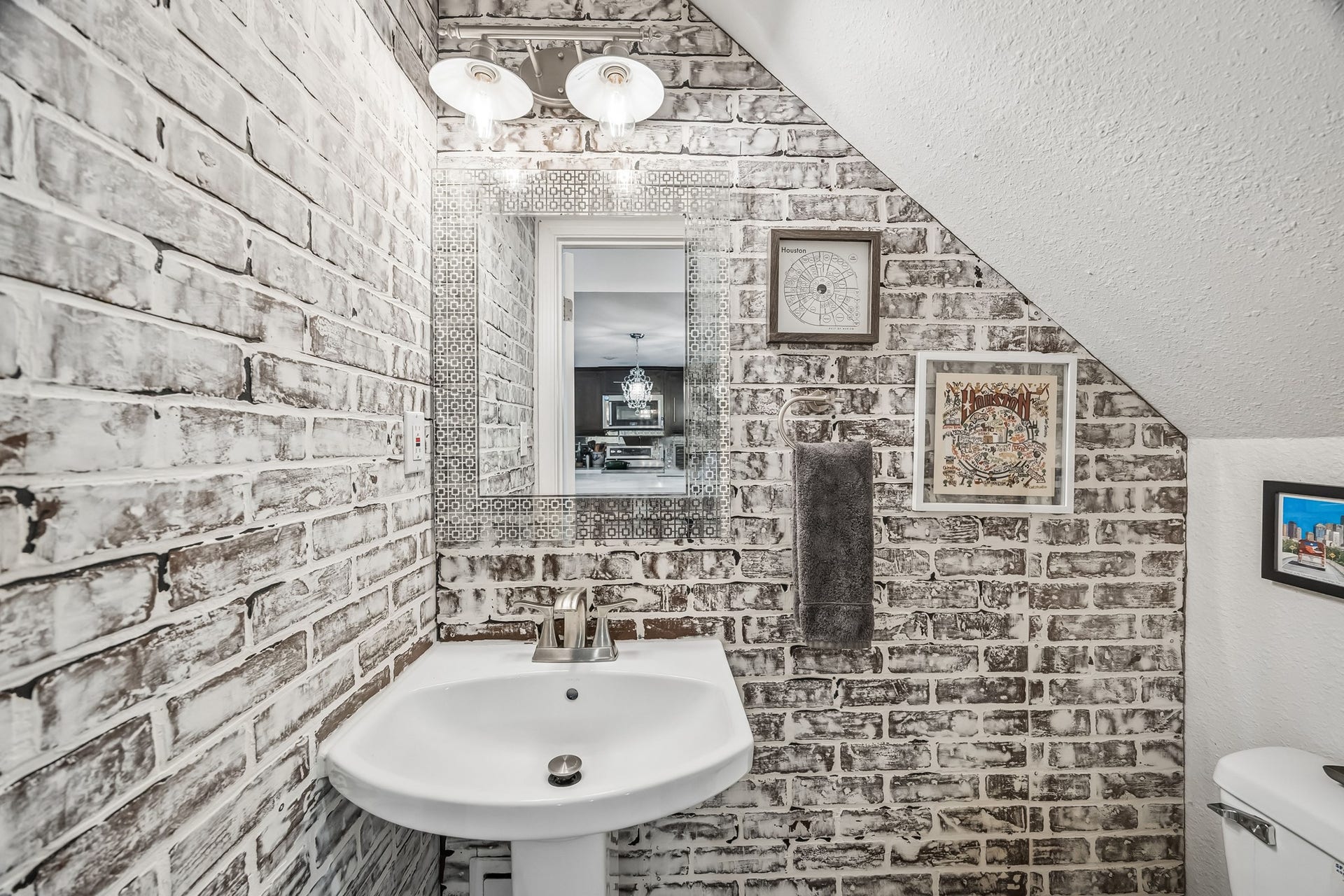 14719 Barryknoll Lane, #51, Houston, TX 77079 The powder bathroom adds a stylish touch with brick-patterned walls, a pedestal sink, and a decorative mirror. Its location beneath the staircase makes smart use of space while keeping a half bath convenient for guests.