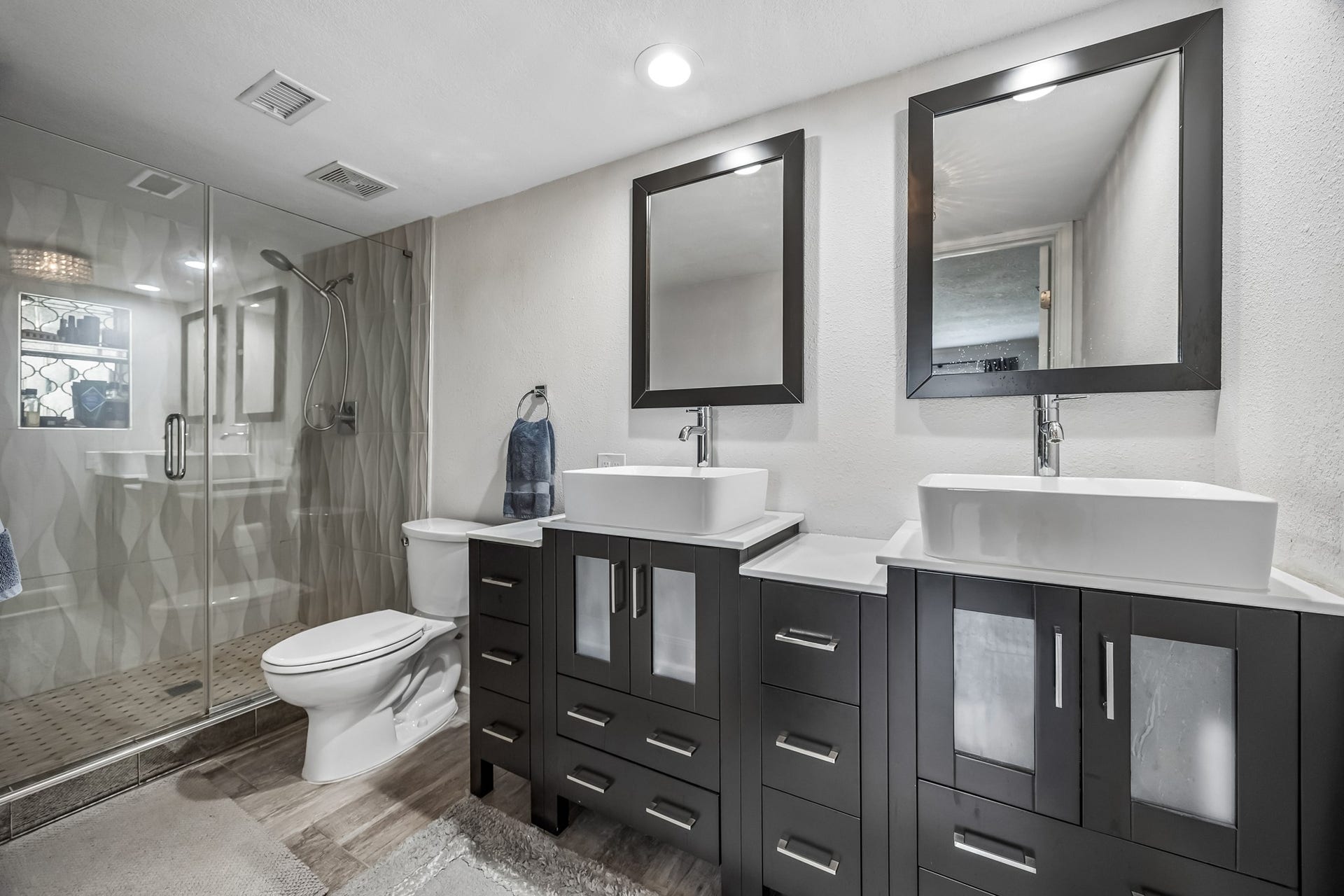 14719 Barryknoll Lane, #51, Houston, TX 77079 Updated primary ensuite features an oversized glass-enclosed oversized walk-in shower creating a clean, modern focal point. Two separate vanities with framed mirrors, and generous storage add function and style.