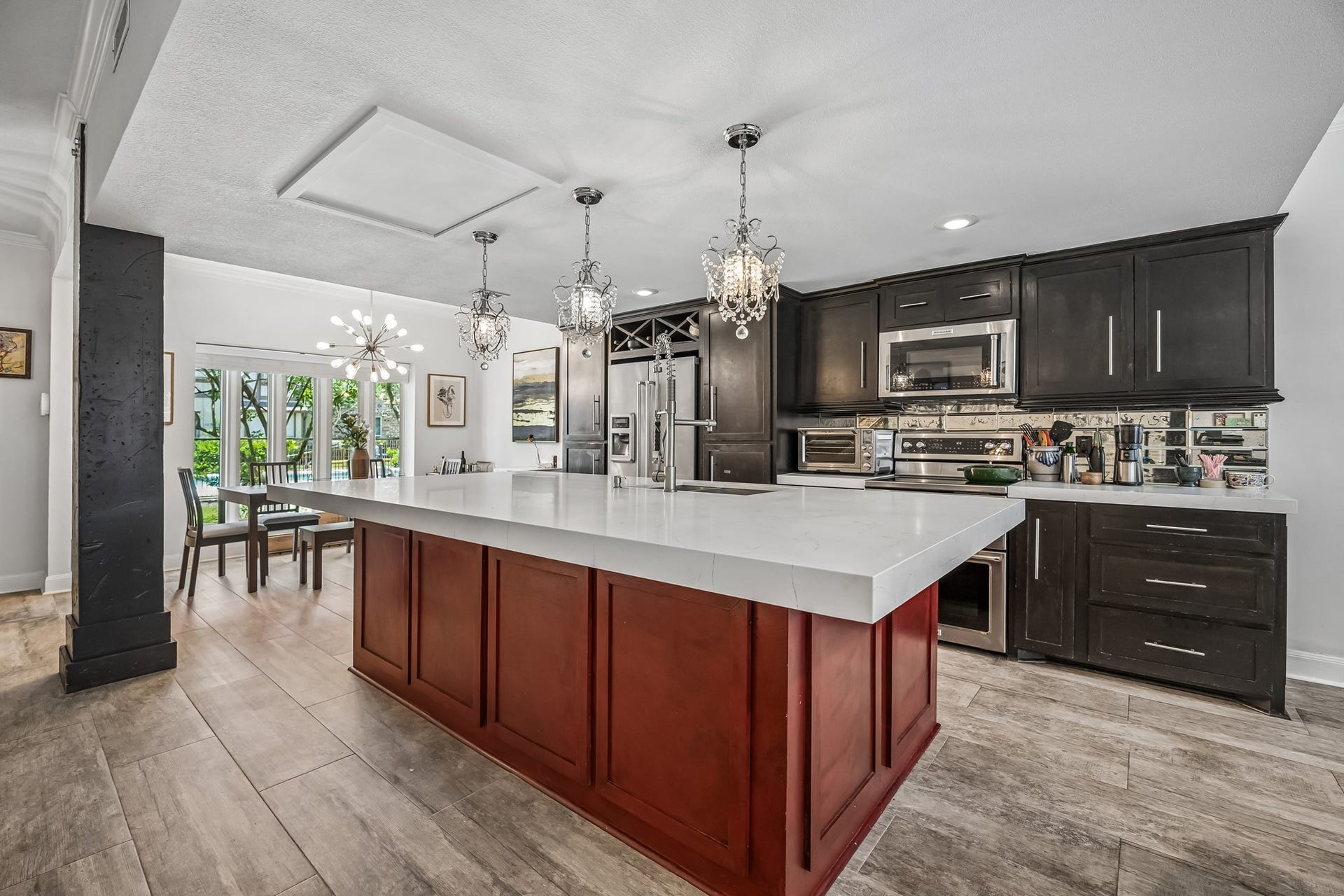 14719 Barryknoll Lane, #51, Houston, TX 77079 The island kitchen offers generous prep space with a wide countertop, deep sink, and pendant lighting overhead. Dark cabinetry, a mirrored tile backsplash, and open views to the dining area give the space a stylish, connected feel.