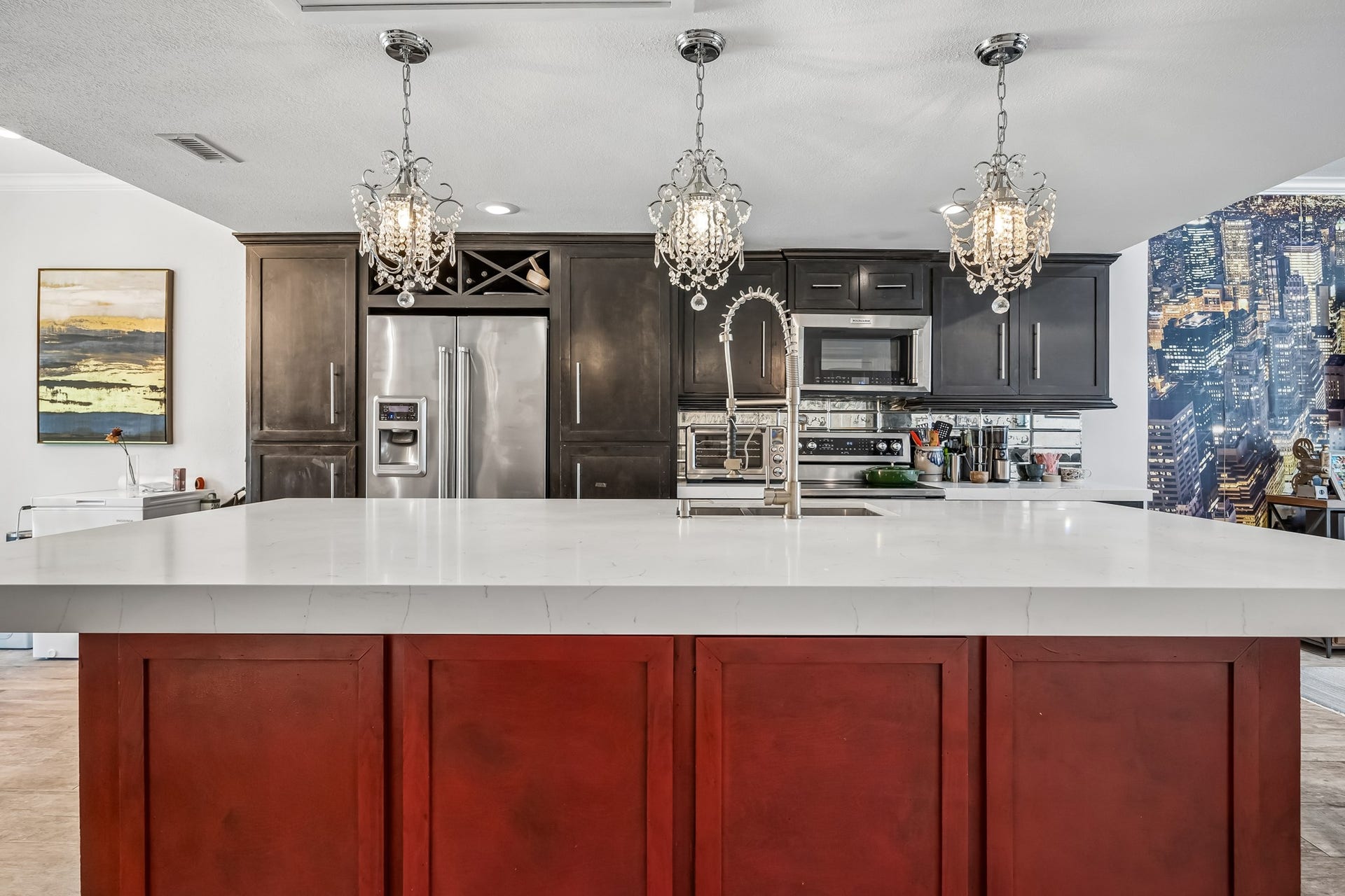 14719 Barryknoll Lane, #51, Houston, TX 77079 The kitchen is anchored by a large island with an expansive countertop, deep sink, and decorative pendant lighting. Dark cabinetry, built-in storage, and a mirrored tile backsplash add both function and visual interest.