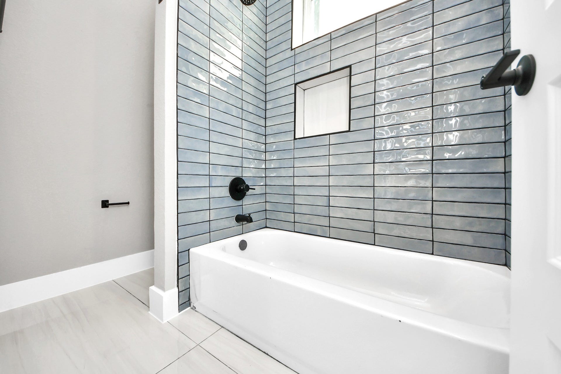 The secondary bathroom pairs a full tub and shower with modern tilework and clean contemporary details.