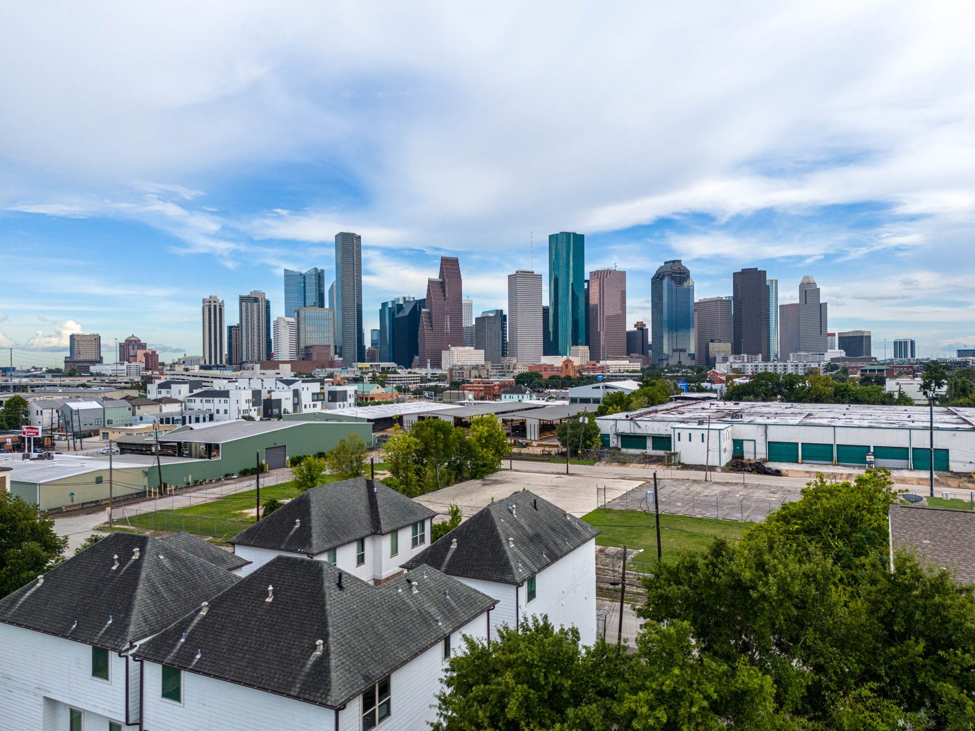 1615 Bingham Street, Houston, TX 77007 Stunning skyline views of downtown Houston, showcasing a blend of modern architecture and vibrant city life, with residential rooftops in the foreground.