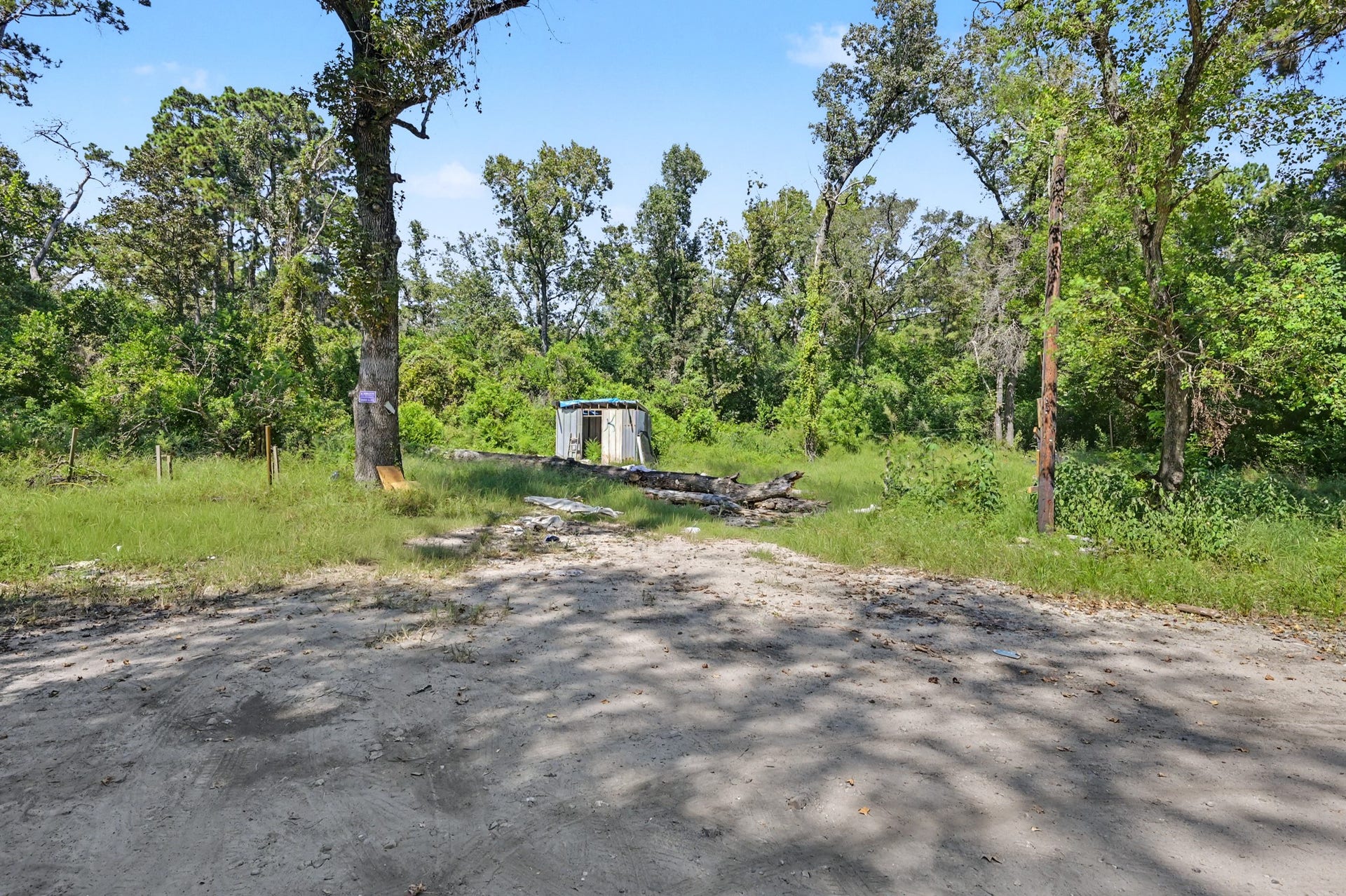 25589 Peach Creek Drive, New Caney, TX 77357 Shaded, level lot showing on-site power connections and clear space for an RV or mobile home setup.