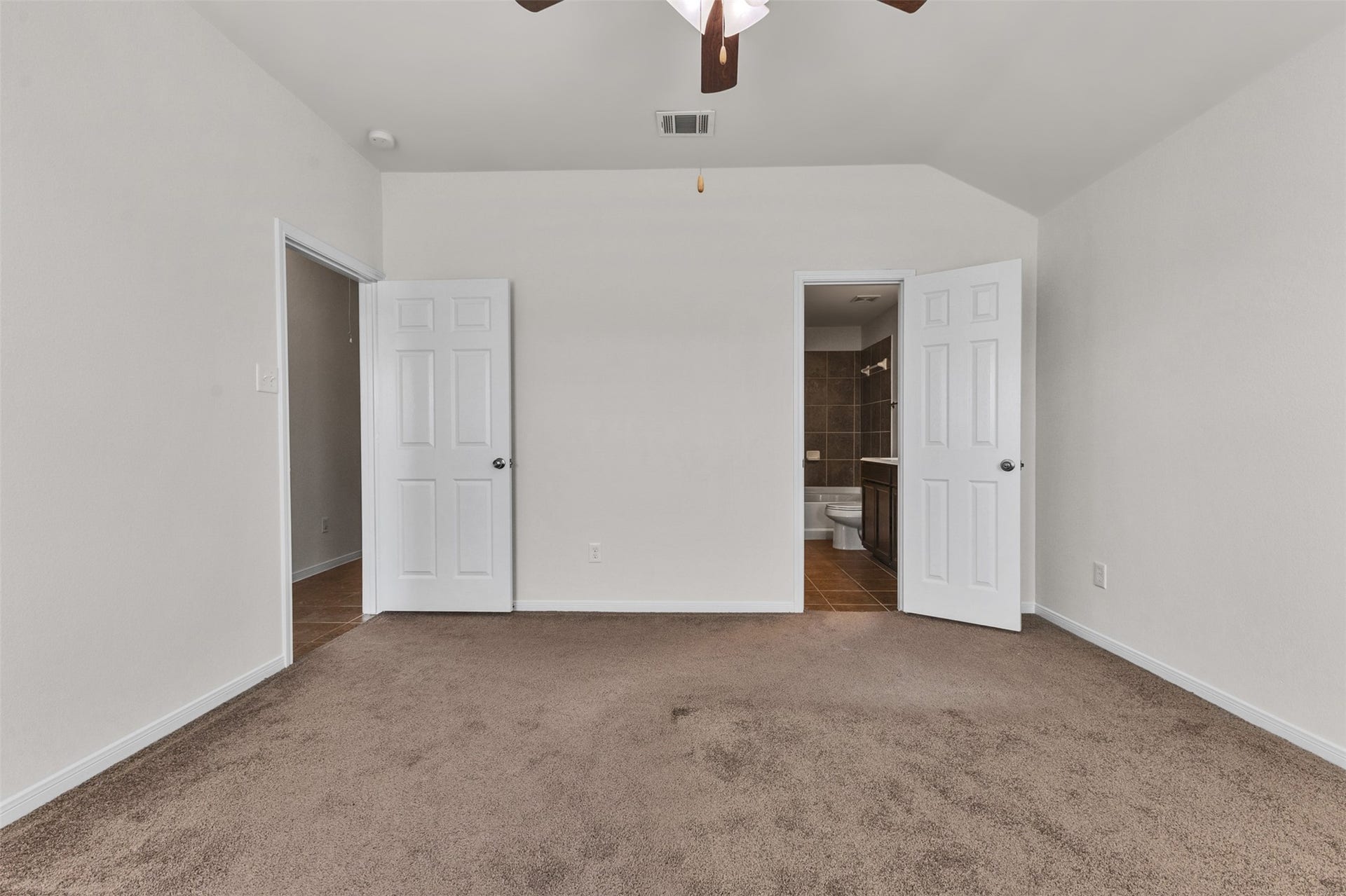 12915 Almeda Crossing Court, Houston, TX 77048 Spacious primary bedroom with ceiling fan and convenient access to the private bath.