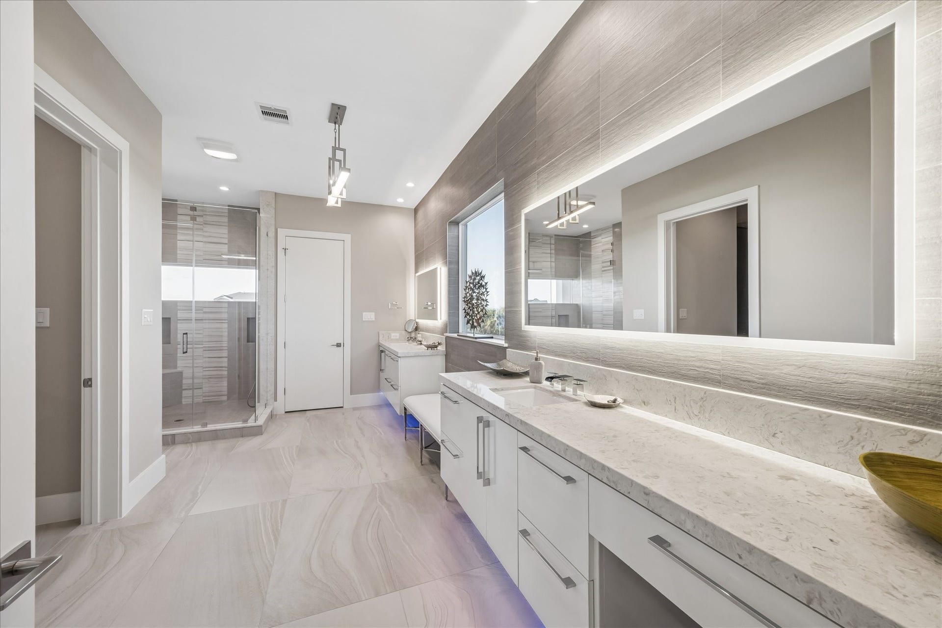 1 Water Key, Hitchcock, TX 77563 The primary ensuite bathroom is bright and modern, featuring an elongated double vanity with quartz countertops, large backlit mirrors, under-vanity lighting, a frameless walk-in shower, and a comfortable sitting area