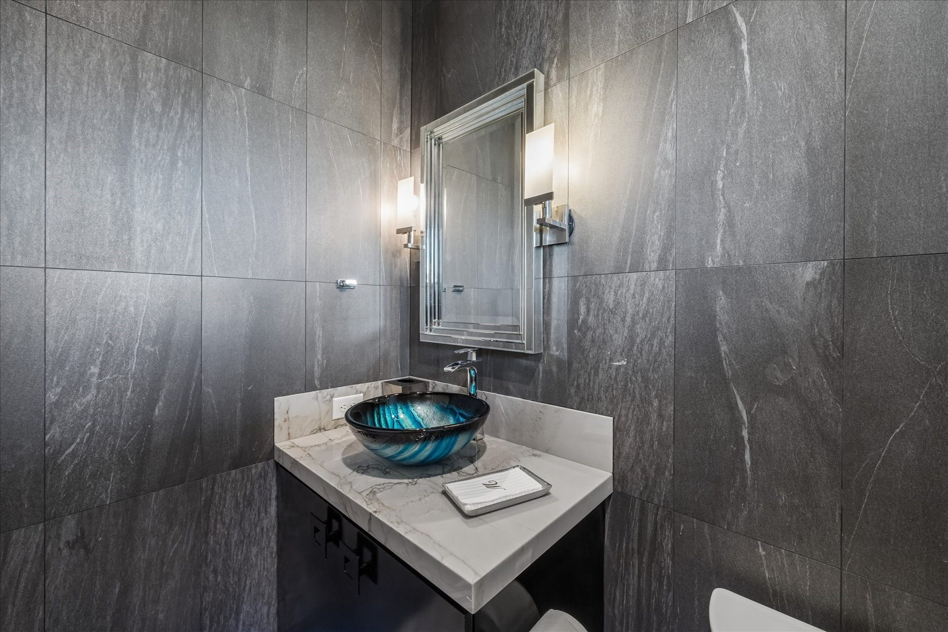 1 Water Key, Hitchcock, TX 77563 The powder room features dramatic wall tile, a stunning glass vessel sink, and quartz countertops, complemented by elegant sconces and a beautifully appointed mirror