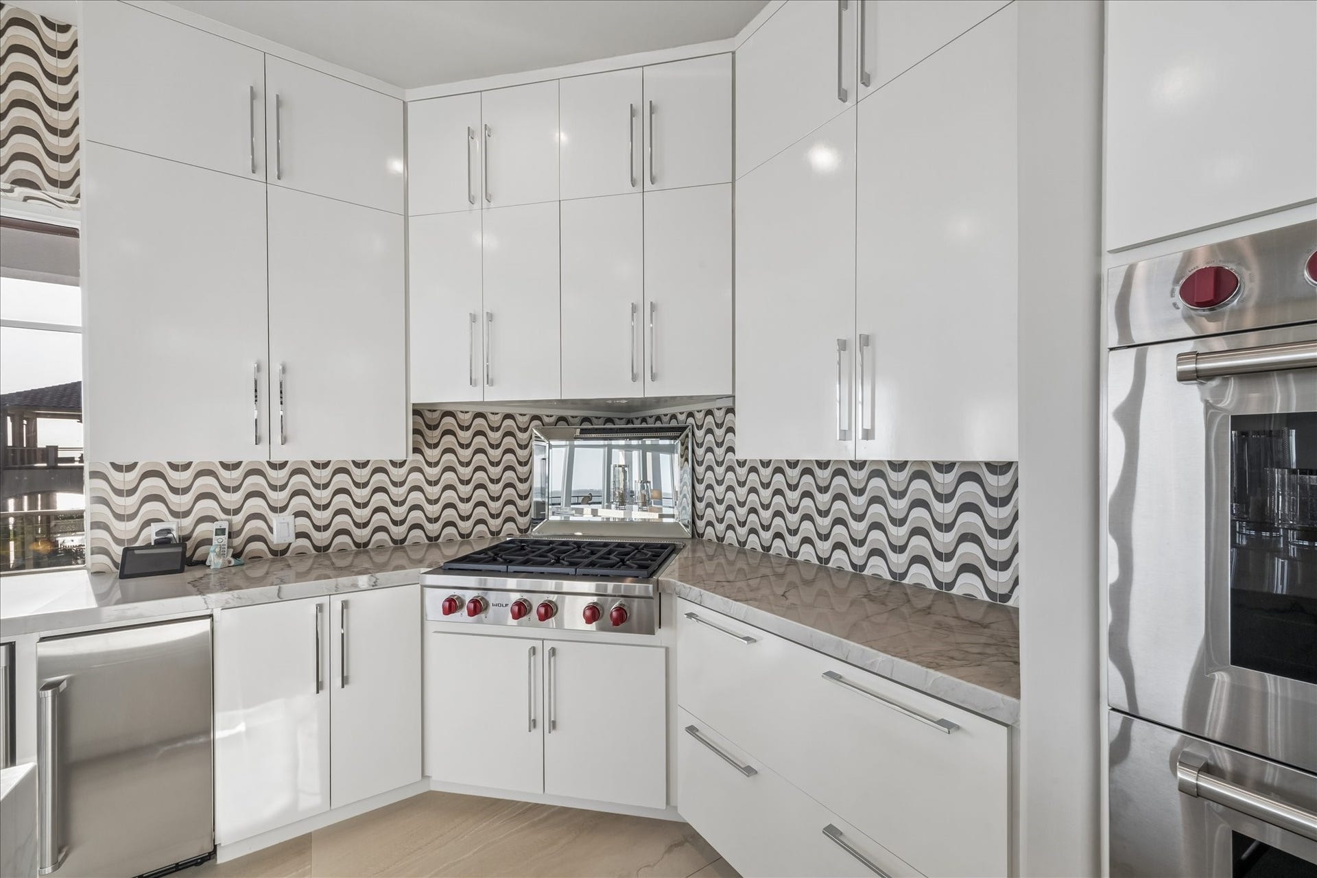 1 Water Key, Hitchcock, TX 77563 A mirrored accent behind the gas cooktop reflects both light and water views, amplifying the rooms bright, airy ambiance. The modern wavy tile backsplash brings depth and a contemporary style to the space