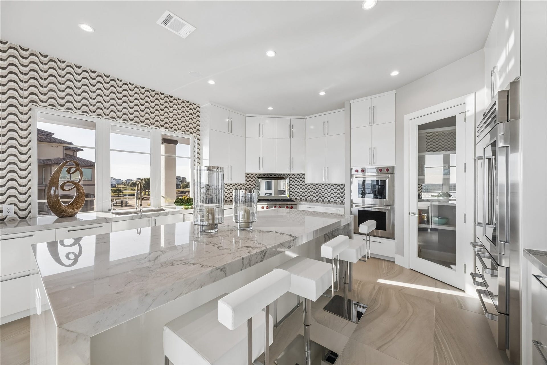 1 Water Key, Hitchcock, TX 77563 Centering the space is a large quartzite waterfall island with breakfast bar, complemented by high-gloss full-height cabinetry with full-extension, soft-close drawers, and a spacious walk-in pantry