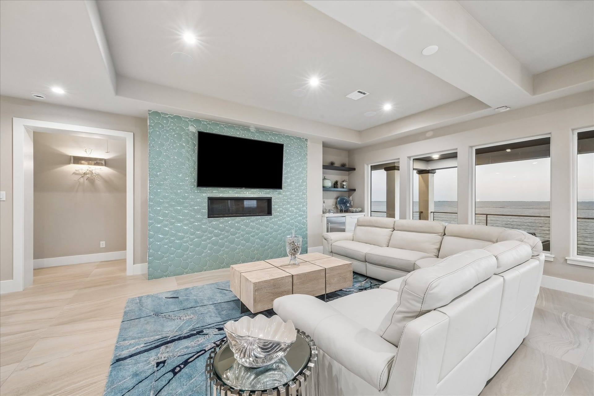 1 Water Key, Hitchcock, TX 77563 Architectural details throughout the space elevate its modern coastal design, featuring recessed tray ceilings with integrated lighting, a built-in dry bar, and a mosaic-tiled accent wall with a linear fireplace