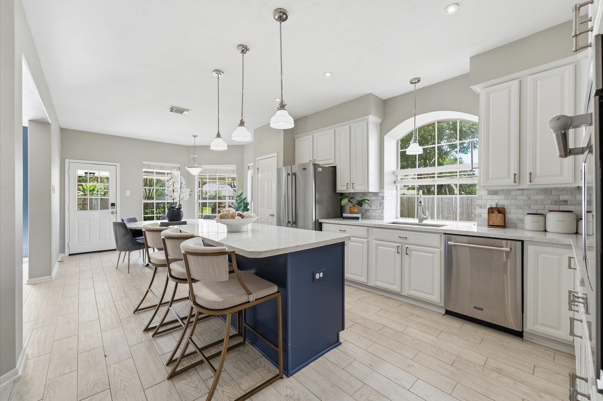 3010 Peekskill Court, Pearland, TX 77584 Kitchen features white cabinetry, island with quartz counters, and stainless steel appliances, with open flow into the living room.