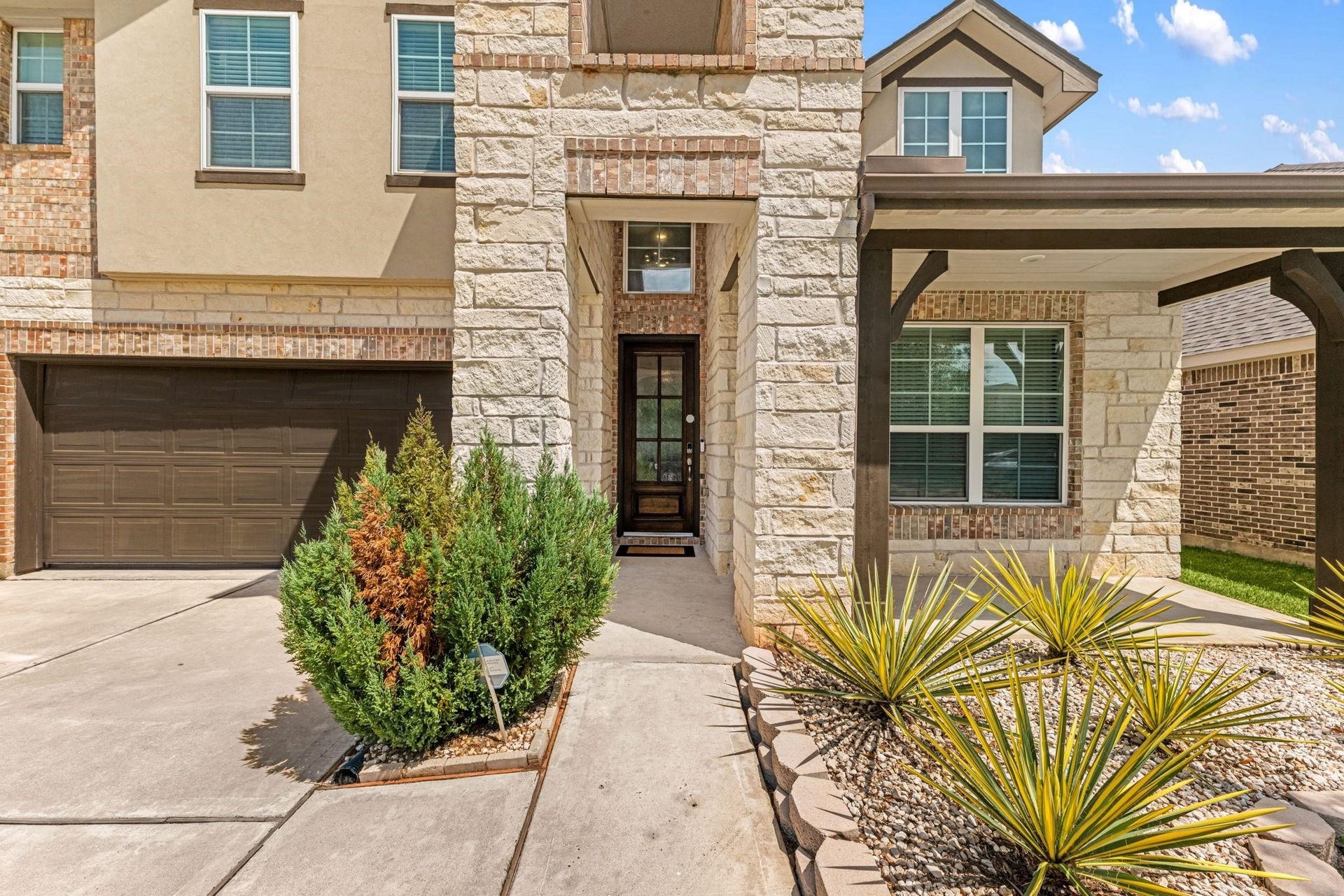 20422 Alpine Meadow Place, Richmond, TX 77407 Tall stone columns and a covered porch create a grand yet welcoming front entryway.