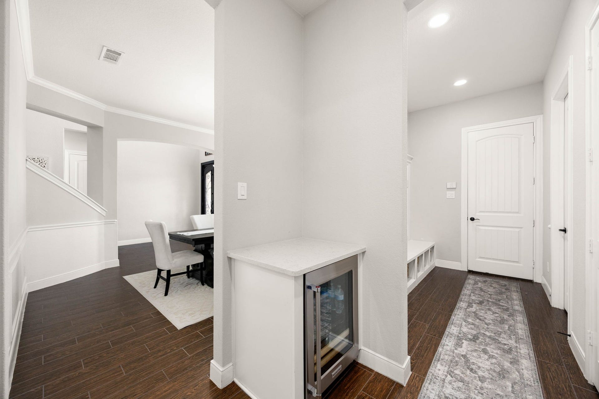 A built-in wine nook sits just off the dining area, leading into a functional mudroom with a bench and cubby storage near the garage entrance.
