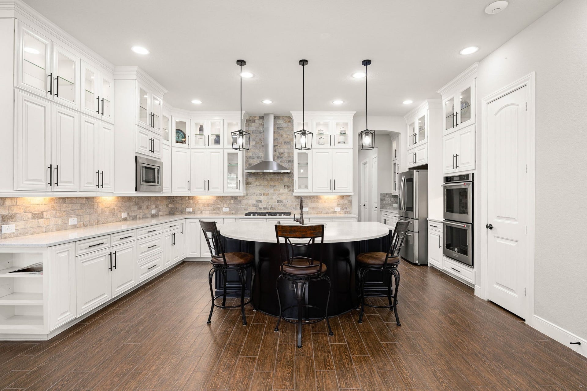 Bright, open and made for gathering, the kitchen pairs floor-to-ceiling cabinetry with an oversized island and plenty of room to pull up a seat.