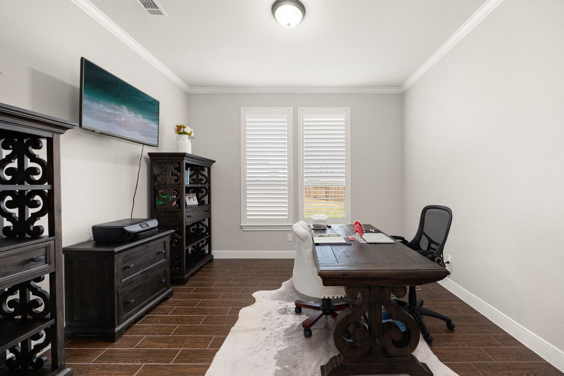 French doors open into a private home office with dark wood built-ins and abundant natural light from the two large windows.
