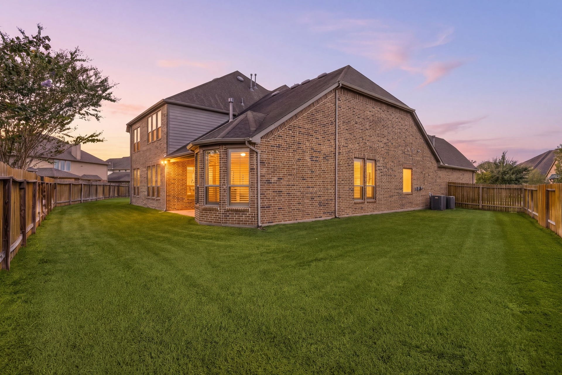 As evening sets in, the backyard offers a peaceful retreat with plenty of green space to unwind.