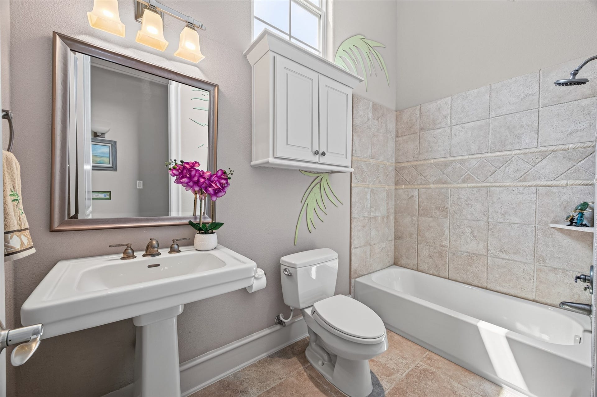 13 Sugarloaf, Hitchcock, TX 77563 Bright and inviting bathroom with elegant tile work, a spacious bathtub, and a pedestal sink under modern lighting.