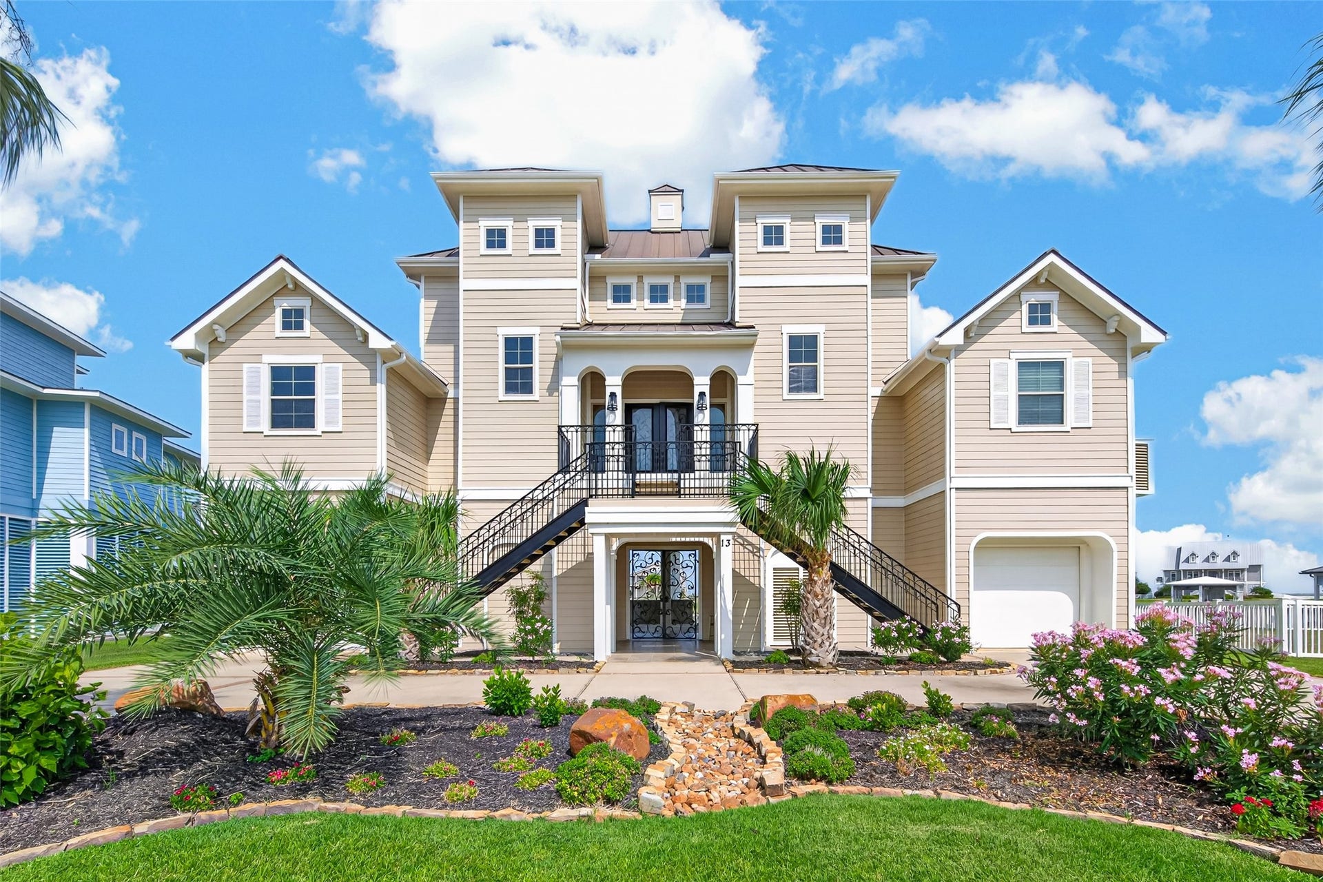 13 Sugarloaf, Hitchcock, TX 77563 Stunning coastal home with elegant architecture, featuring dual staircases, a welcoming balcony, and lush landscaping.