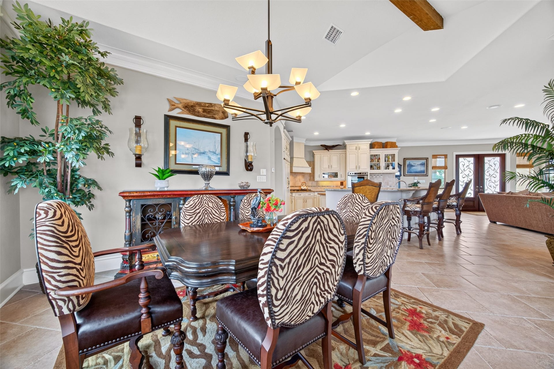 13 Sugarloaf, Hitchcock, TX 77563 Elegant open-concept dining and kitchen area featuring a stylish chandelier, zebra-patterned chairs, and a spacious layout that flows seamlessly into the living room.
