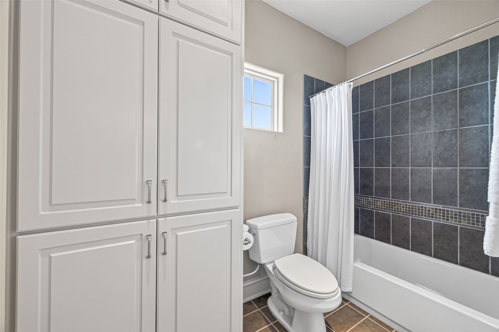 13 Sugarloaf, Hitchcock, TX 77563 Bright bathroom featuring elegant dark tile in the shower, abundant cabinet storage, and a convenient window for natural light.