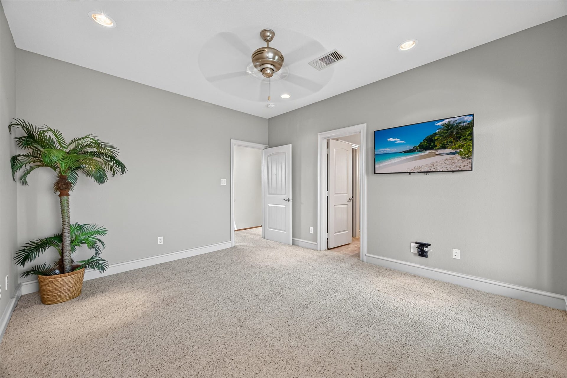 13 Sugarloaf, Hitchcock, TX 77563 Spacious bedroom featuring plush carpeting, a modern ceiling fan, and a wall-mounted TV, with soft neutral walls and abundant natural light.