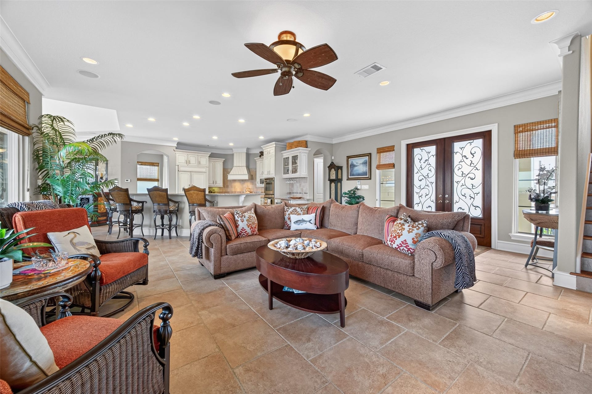 13 Sugarloaf, Hitchcock, TX 77563 Spacious open-concept living area featuring a cozy sectional, elegant ceiling fan, and abundant natural light, seamlessly flowing into a modern kitchen with a breakfast bar and stylish cabinetry.