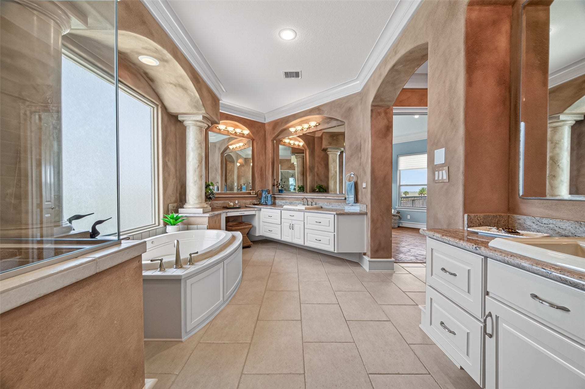 13 Sugarloaf, Hitchcock, TX 77563 Luxurious bathroom featuring a spacious soaking tub, elegant columns, dual vanities with granite countertops, and a soothing ambiance with warm tones and natural light.