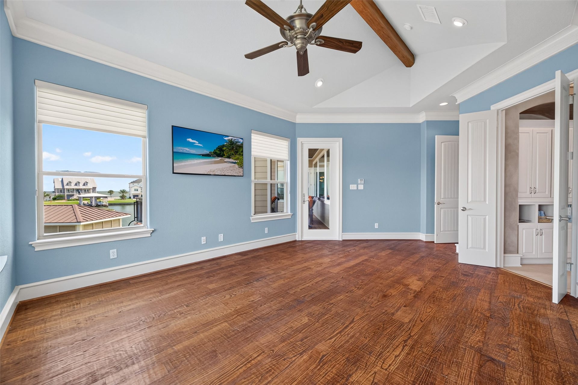 13 Sugarloaf, Hitchcock, TX 77563 Spacious room with elegant hardwood floors, vaulted ceiling with wooden beams, and abundant natural light from large windows.