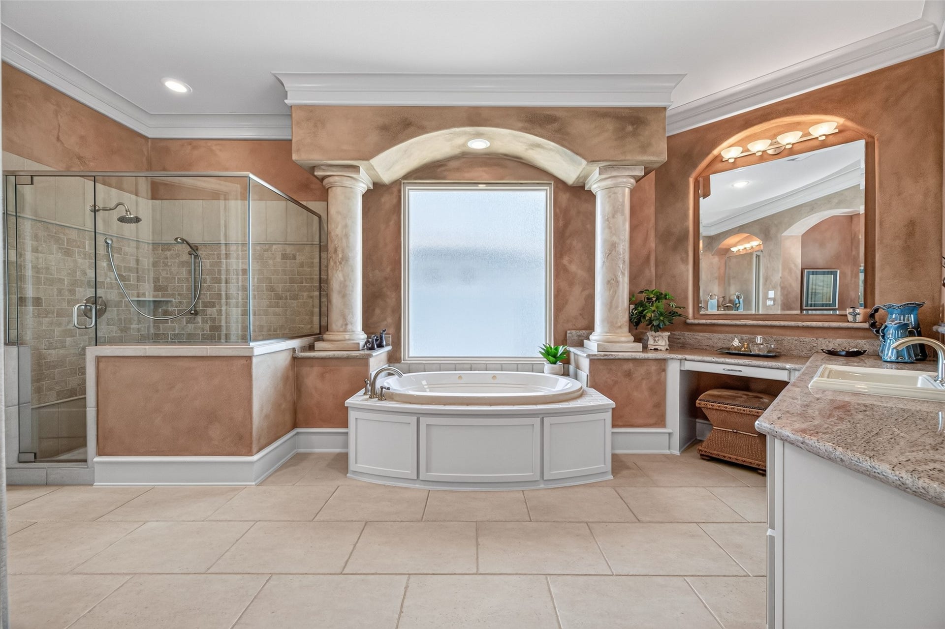 13 Sugarloaf, Hitchcock, TX 77563 Luxurious bathroom featuring a central soaking tub framed by elegant columns, a spacious glass-enclosed shower, and dual vanities with rich granite countertops for a spa-like experience.