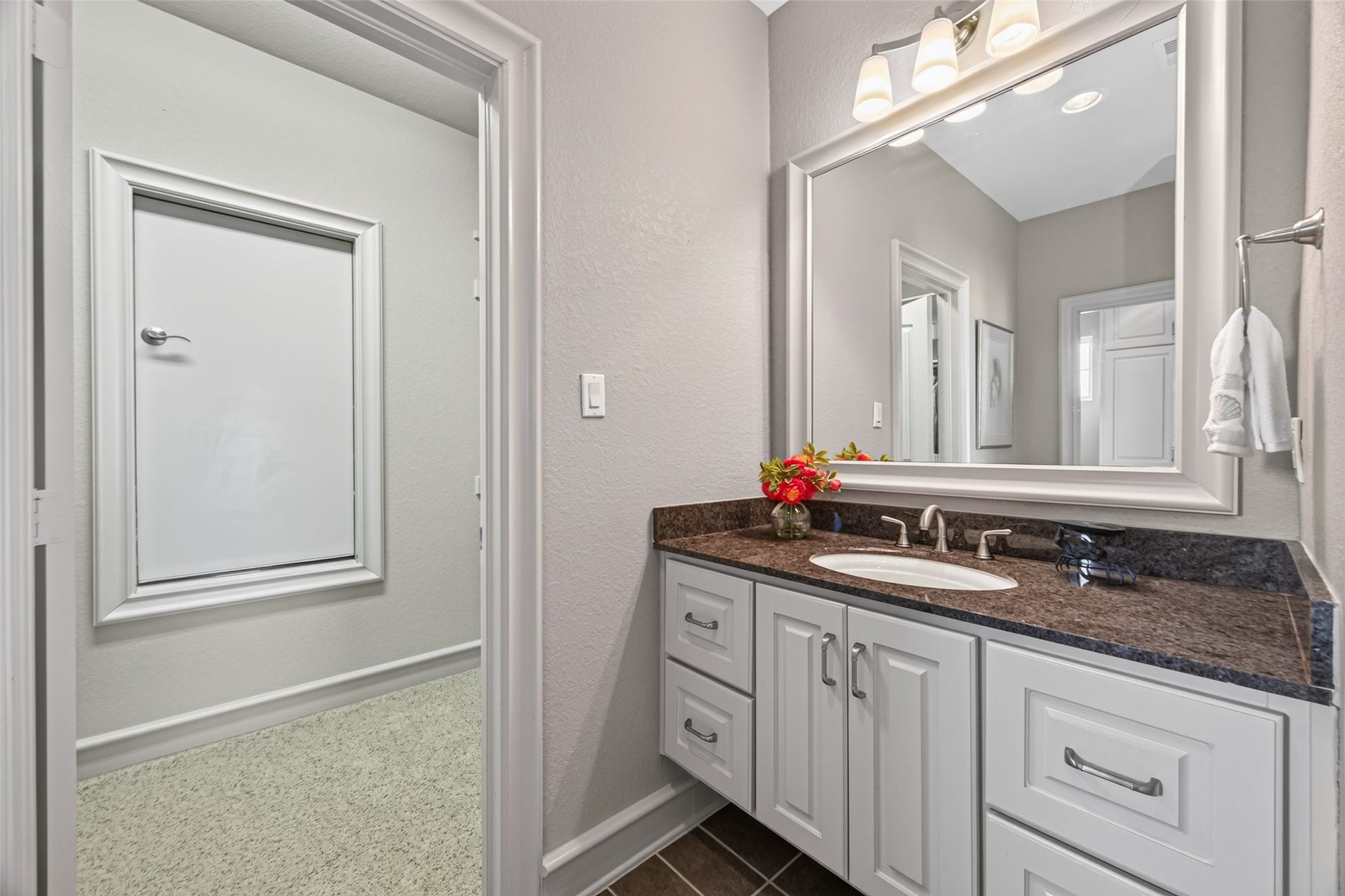 13 Sugarloaf, Hitchcock, TX 77563 Elegant bathroom with a sleek vanity featuring dark granite countertops, ample storage, and a large framed mirror, complemented by soft overhead lighting for a tranquil ambiance.