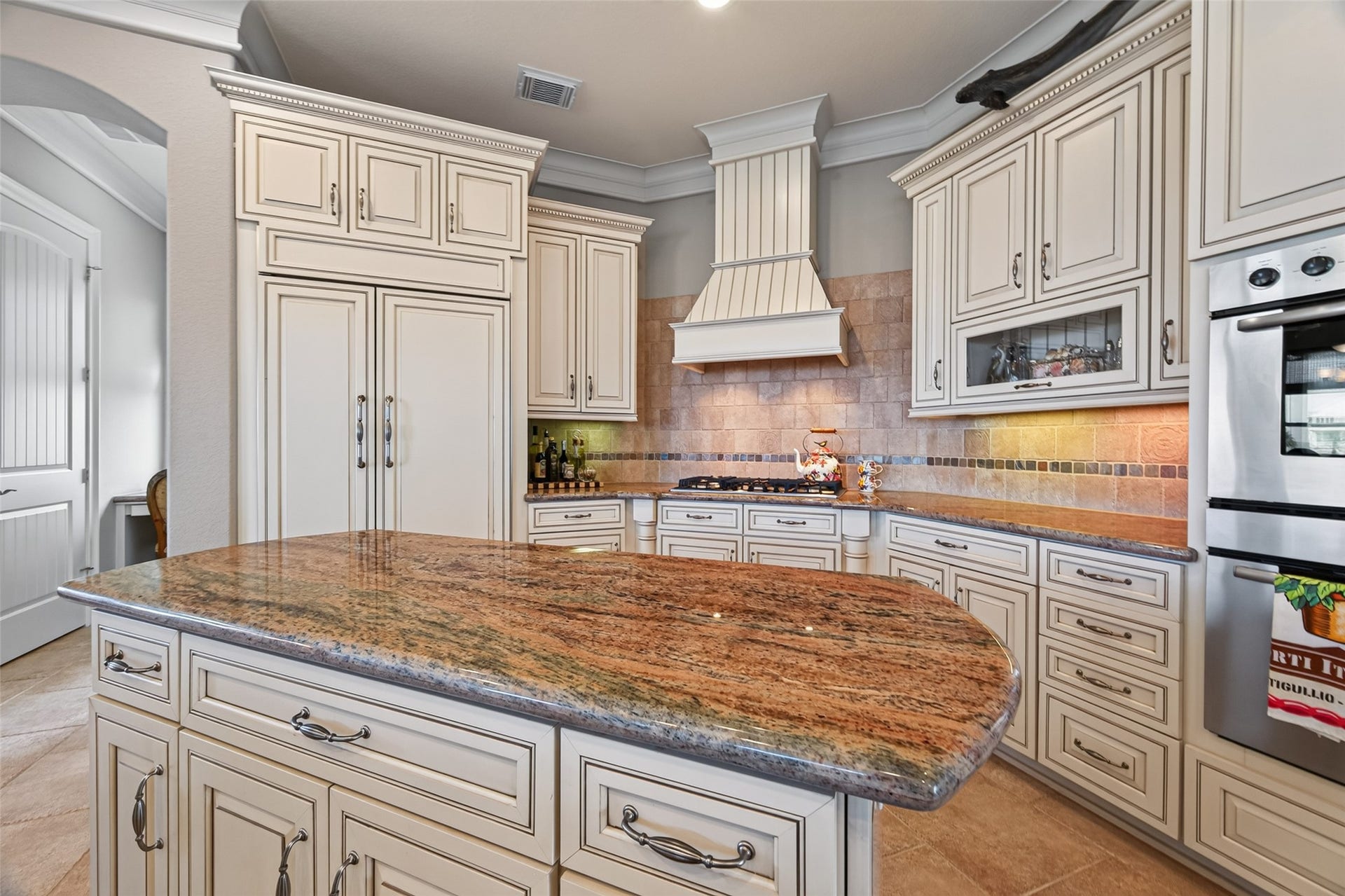 13 Sugarloaf, Hitchcock, TX 77563 Elegant kitchen featuring custom cabinetry, a sleek granite island, and a stylish range hood, perfect for culinary enthusiasts.