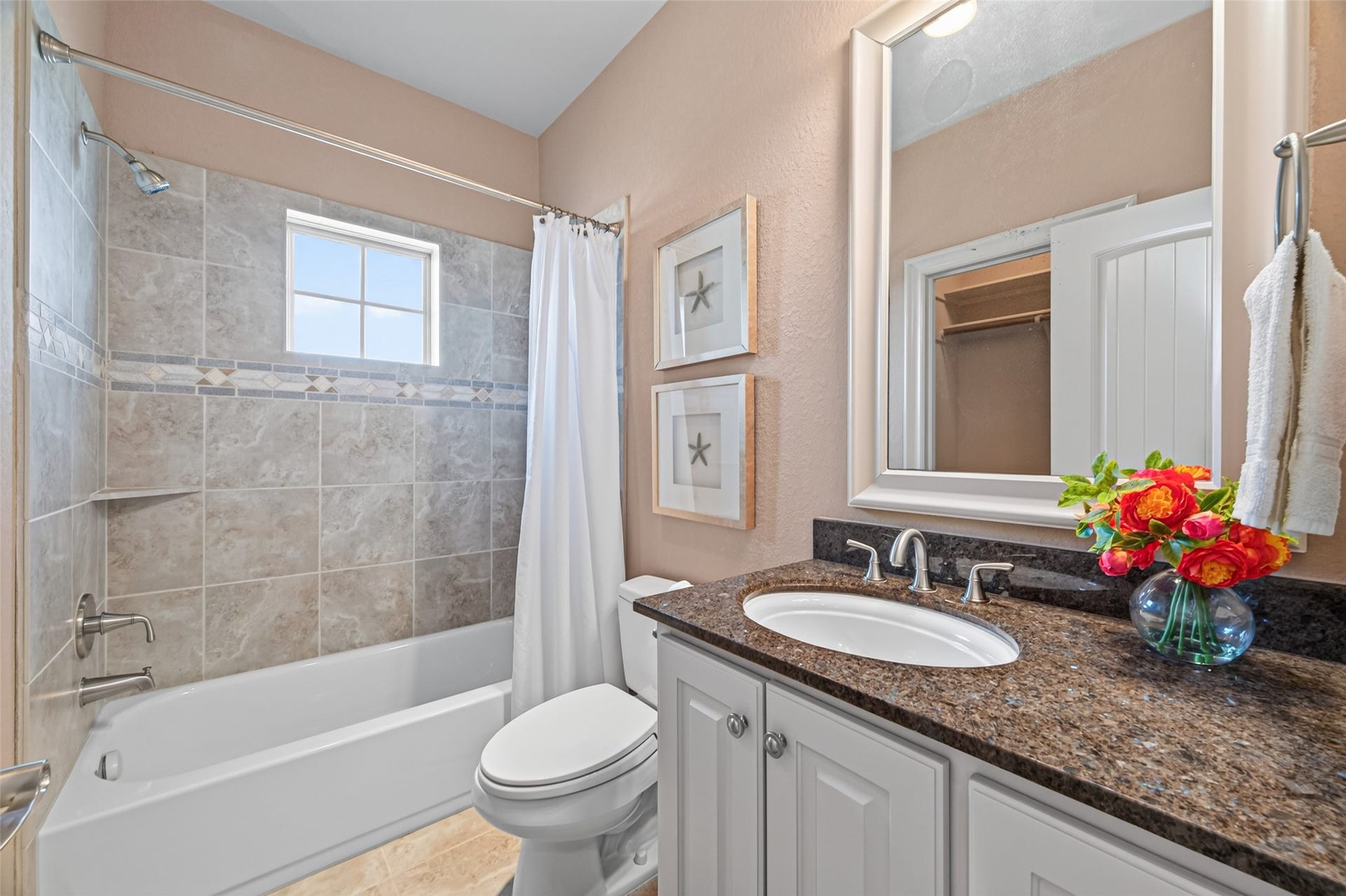 13 Sugarloaf, Hitchcock, TX 77563 Charming bathroom with a granite-topped vanity, bright tile accents, and a shower-tub combo, enhanced by natural light from a window.